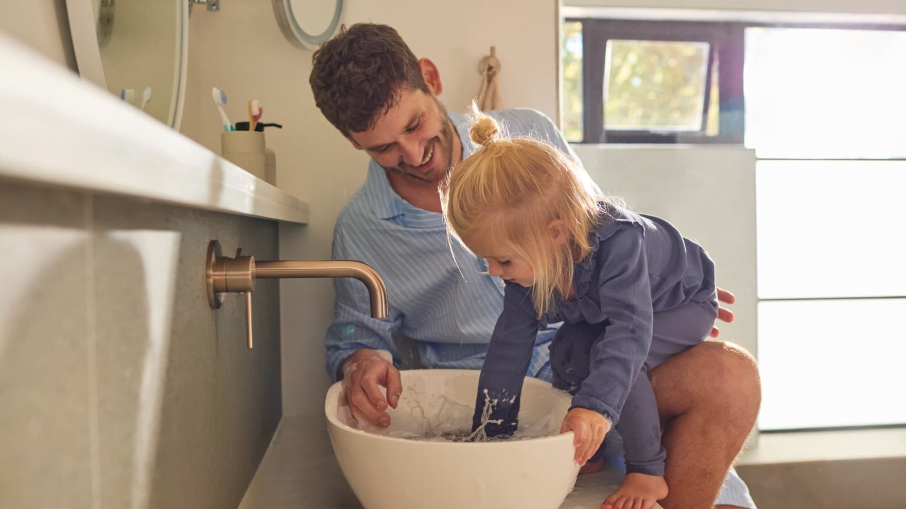 Kleines Mädchen und ihr Vater an einem Waschbecken.