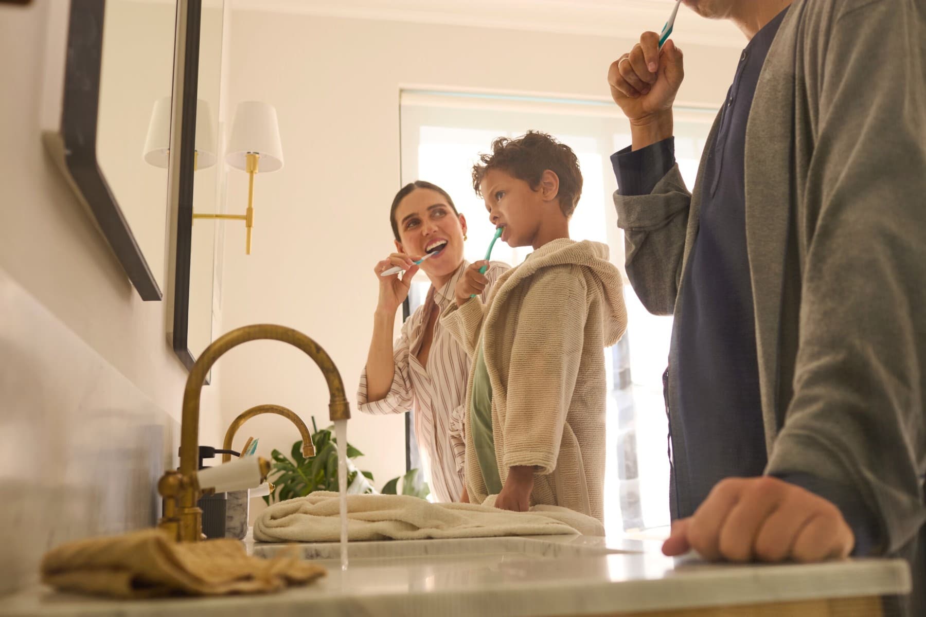 Eine Familie steht im Bad vor einem Waschbecken und putzt sich die Zähne.
