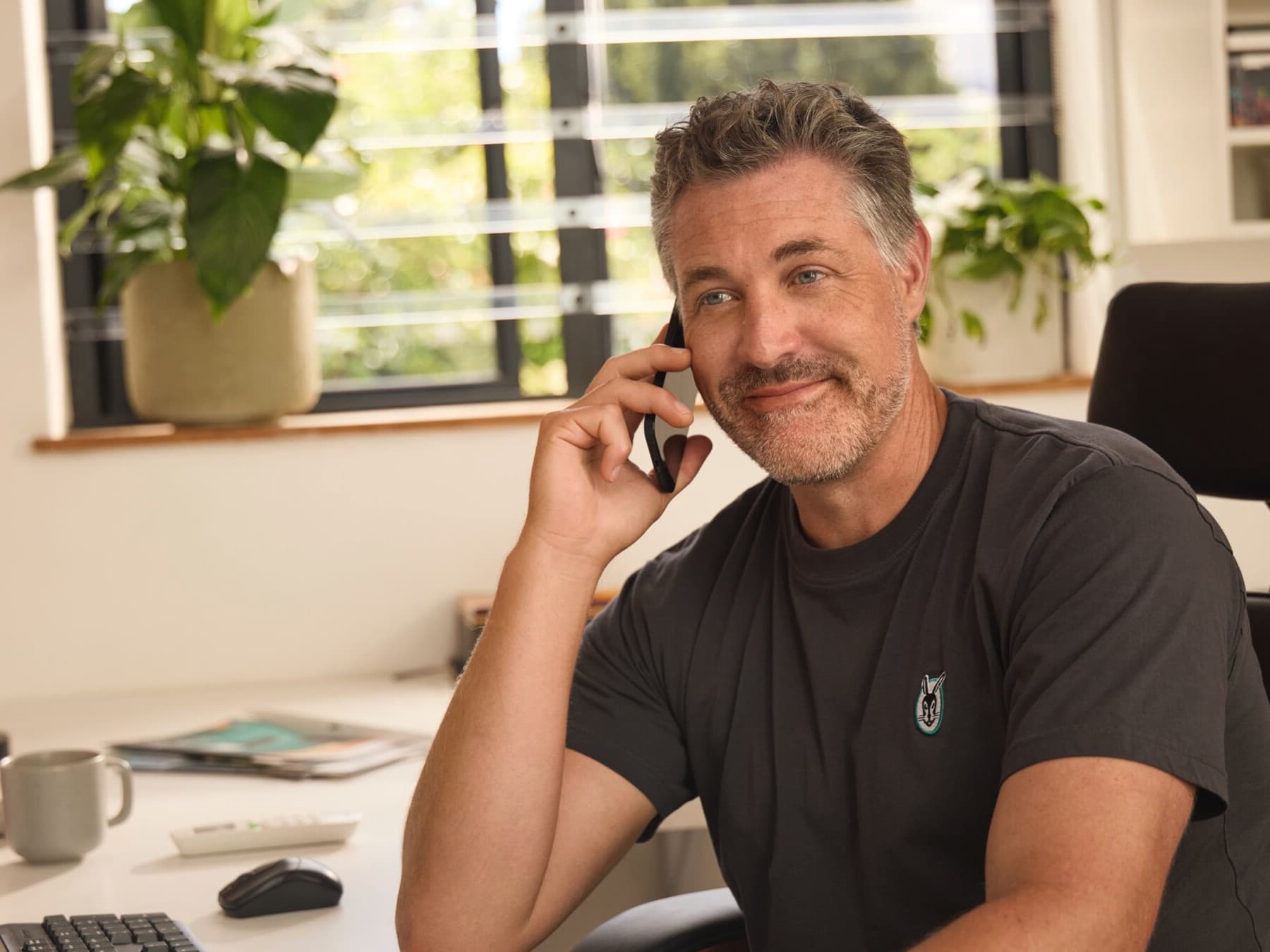 Vaillant Experte sitzt im Büro und hält ein Smartphone in der Hand.