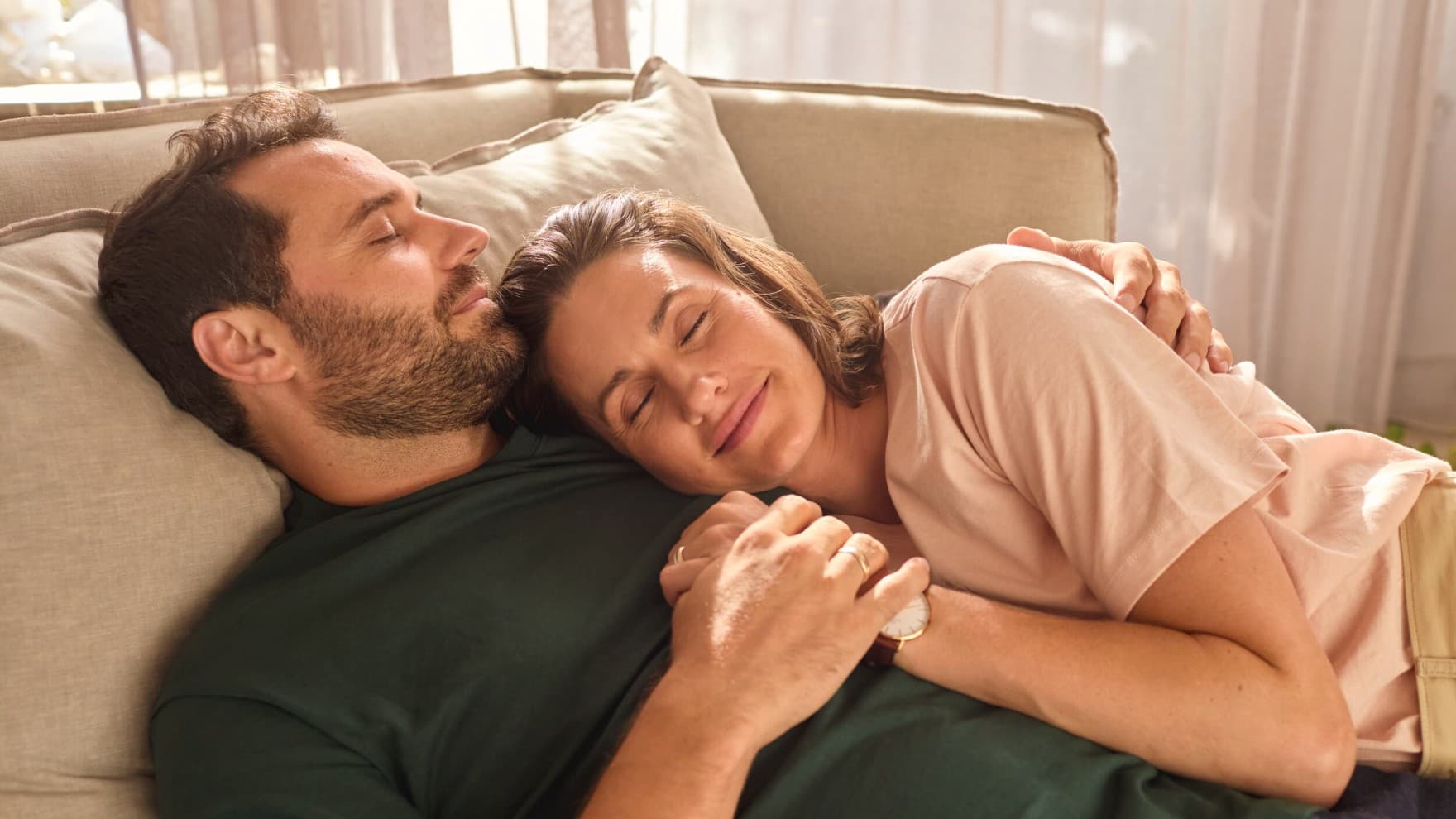 Ein Paar liegt kuschelnd bei angenehmer Raumtemperatur auf der Couch