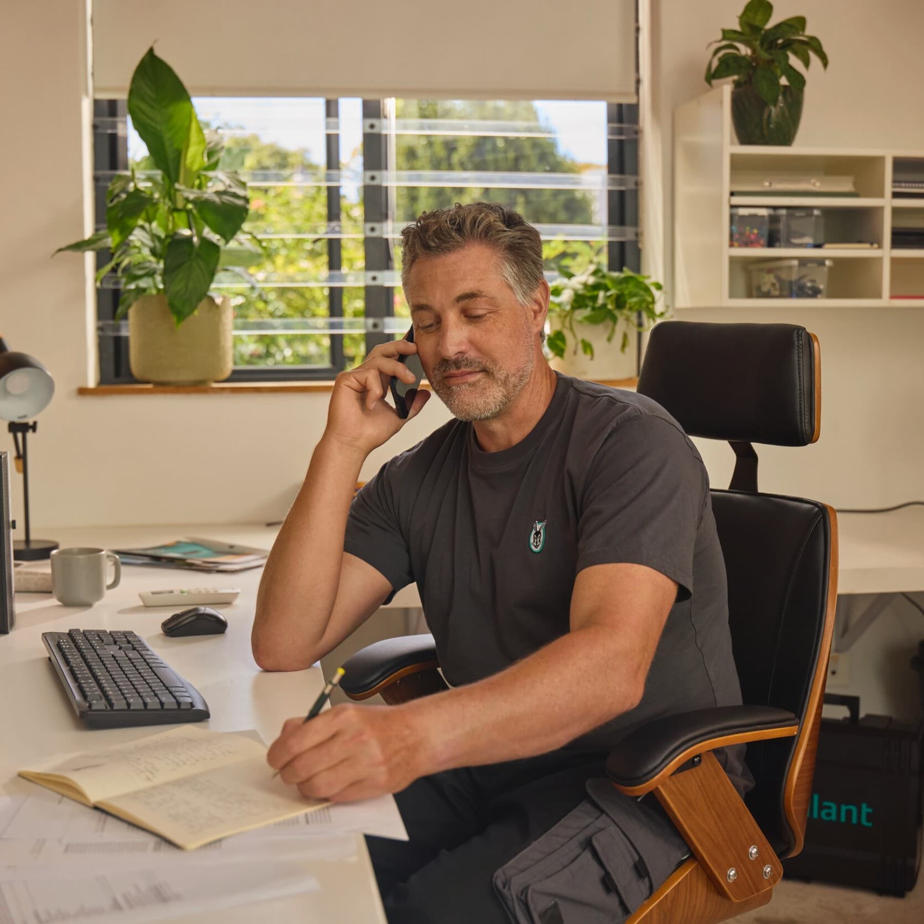 Vaillant Fachpartner sitzt an einem Schreibtisch vor einem PC mit dem Telefon am Ohr.