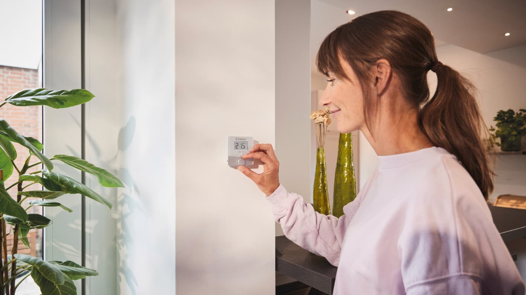 Woman using the Vaillant thermostat sensoROOM