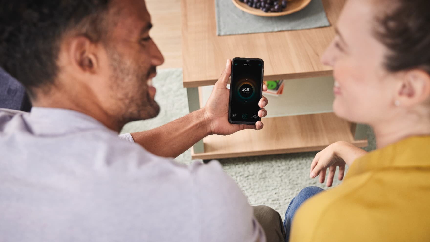 Ein Mann und eine Frau schauen sich die Heizungsregelung auf einem Smartphone an.