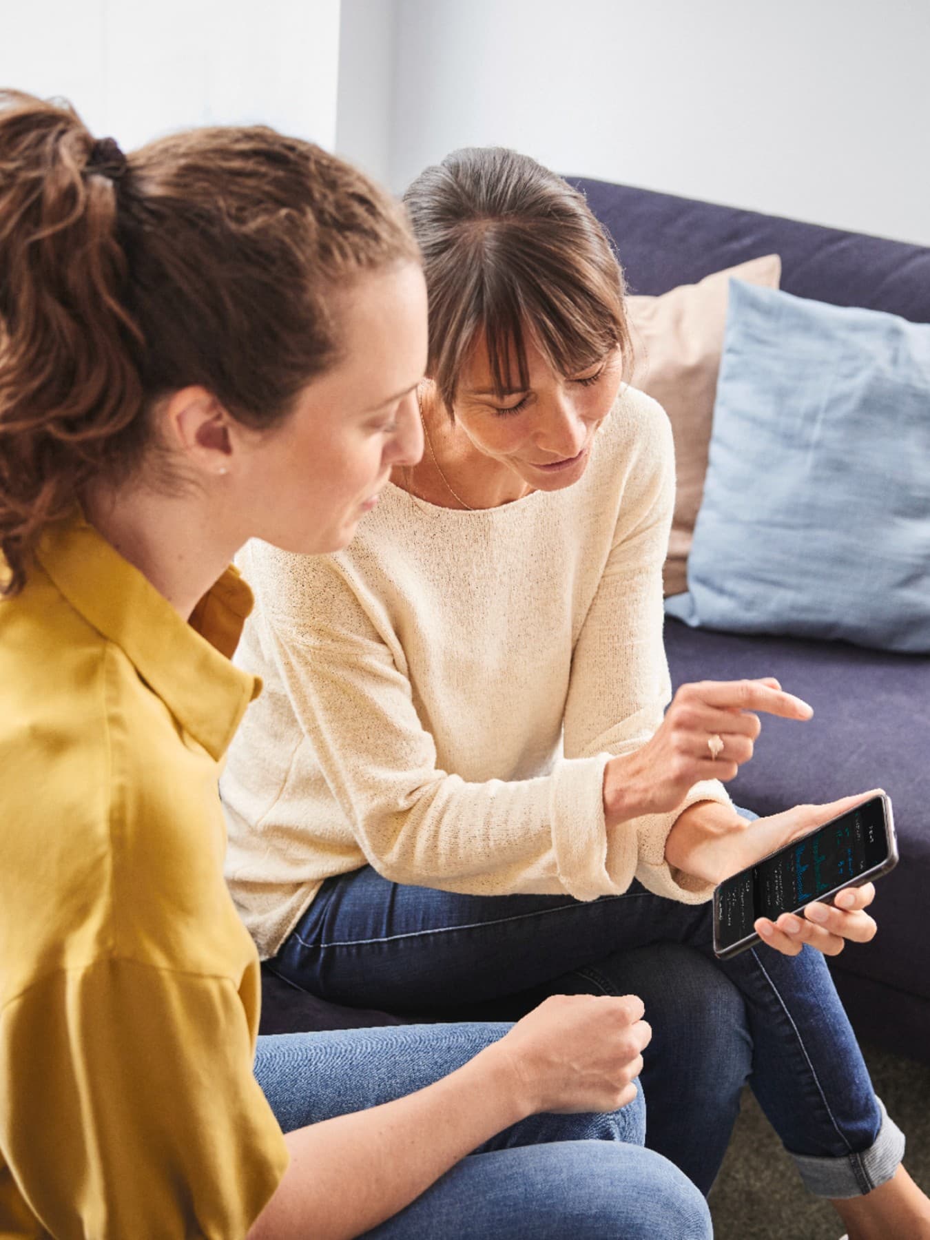 Zwei Frauen, die gemeinsam auf ein Smartphone gucken.