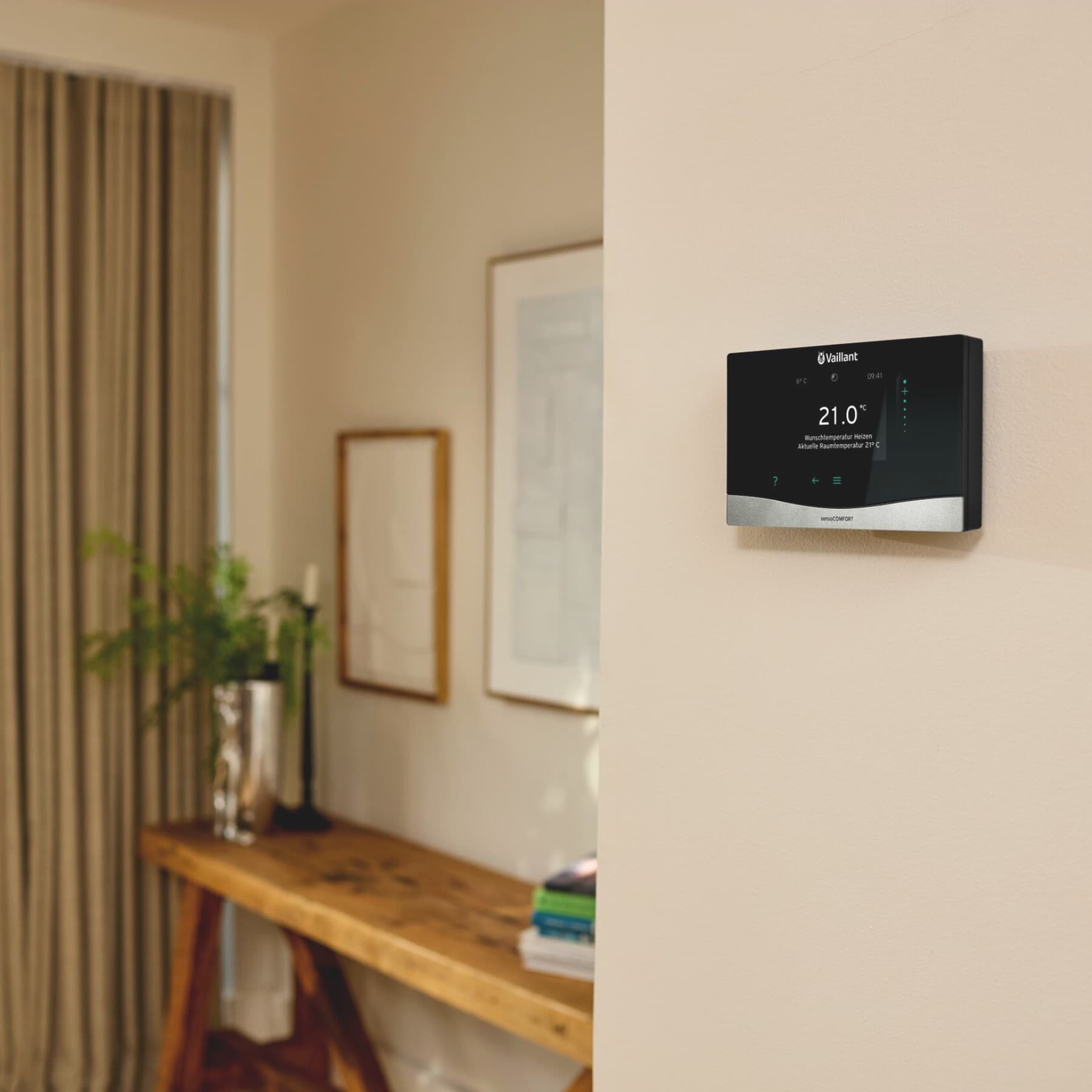 Vaillant Systemregler sensoCOMFORT hängt im Wohnzimmer an einer beigen Wand.