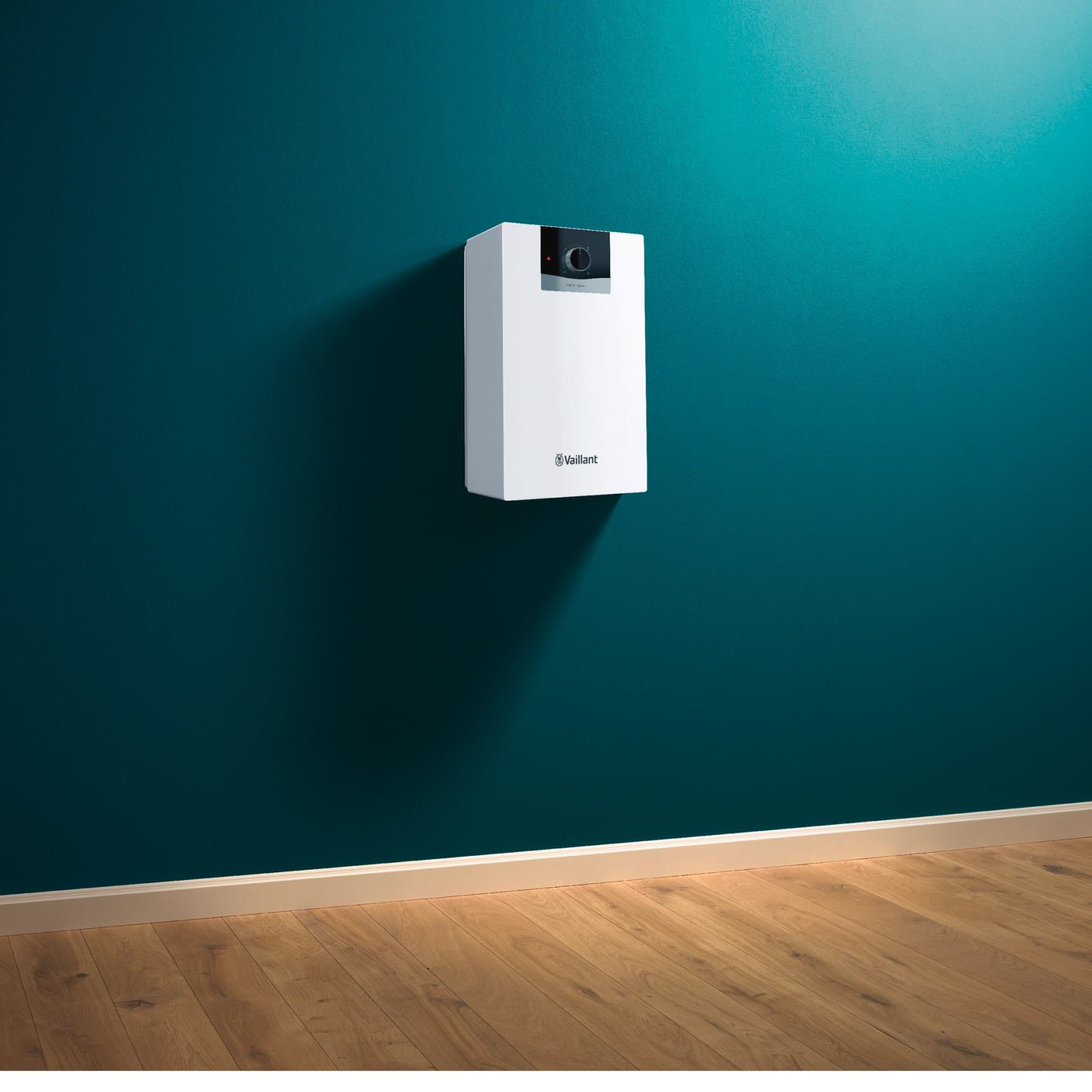 Ein Warmwasserspeicher von Vaillant hängt an einer grünen Wand.