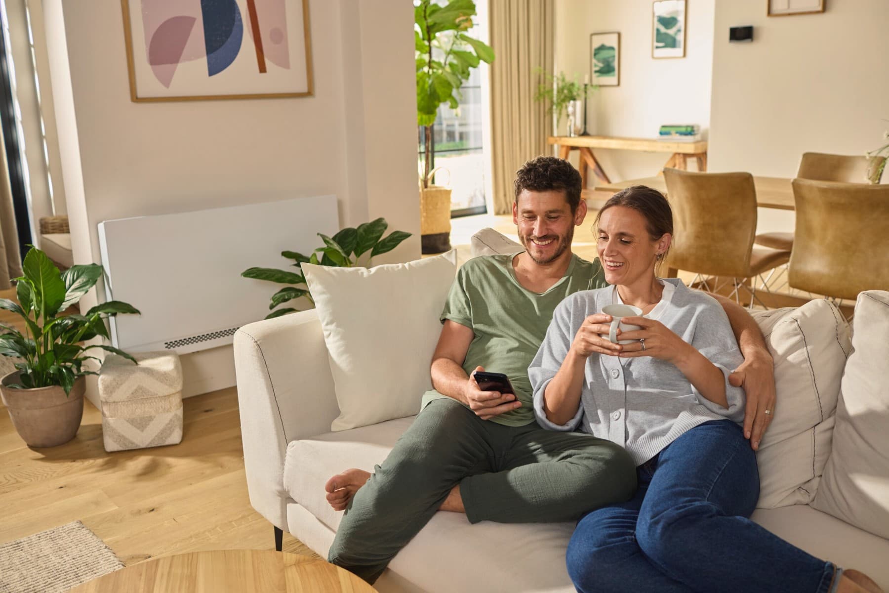 Ein Paar sitzt auf dem Sofa und schaut auf ein Smartphone