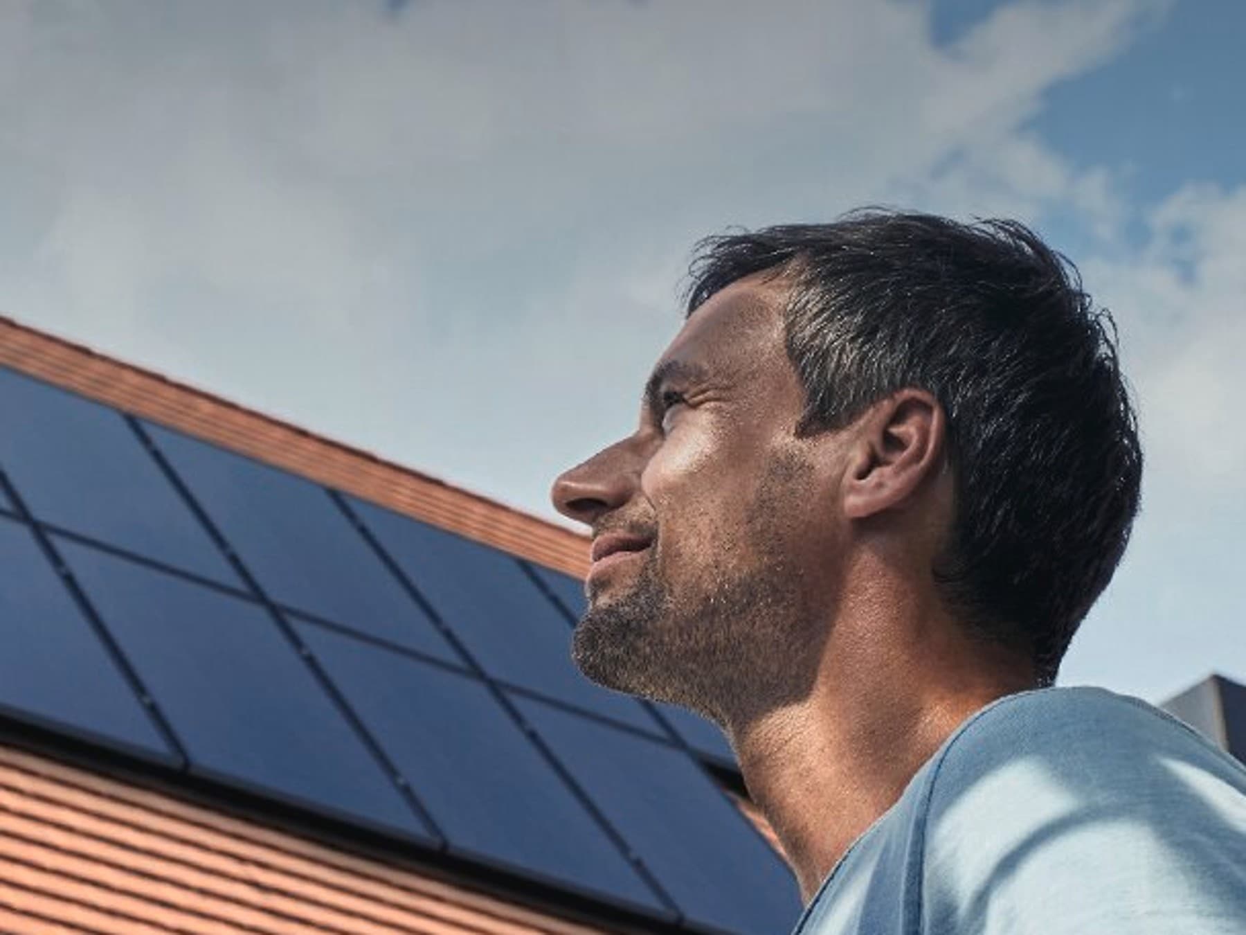 Eigenheimbesitzer schaut auf seine Photovoltaikanlage auf dem Dach
