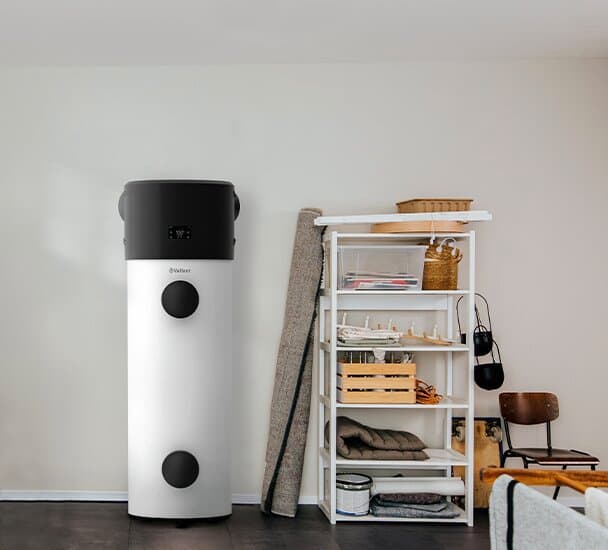 Eine Vaillant Wärmepumpe aroSTOR plus steht neben einem vollen Schwerlastregal.