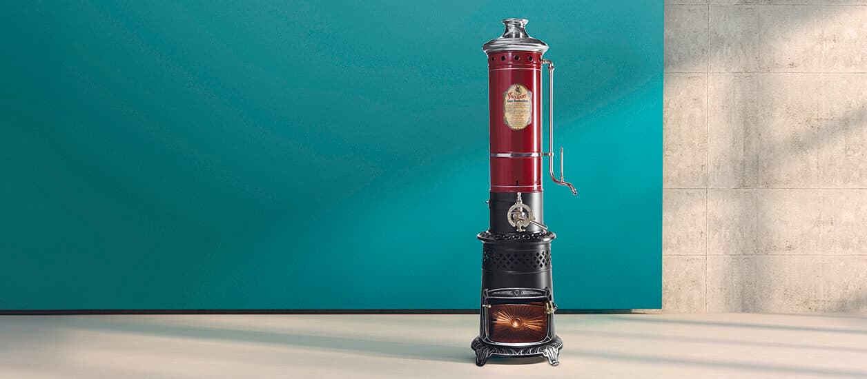 Ein alter Vaillant Geyser in rot-schwarz steht vor einem grünen Hintergrund.