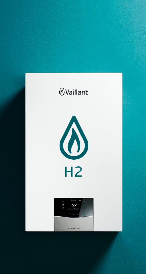 Ein Vaillant ecoTEC Gerät hängt an einer grünen Wand. Auf dem Gerät ist ein großer Wassertropfen und H2 abgebildet.