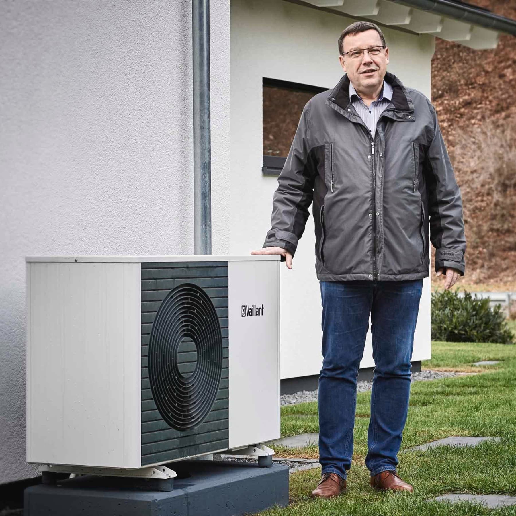 Ein Mann steht vor der Wärmepumpen Außeneinheit im Garten