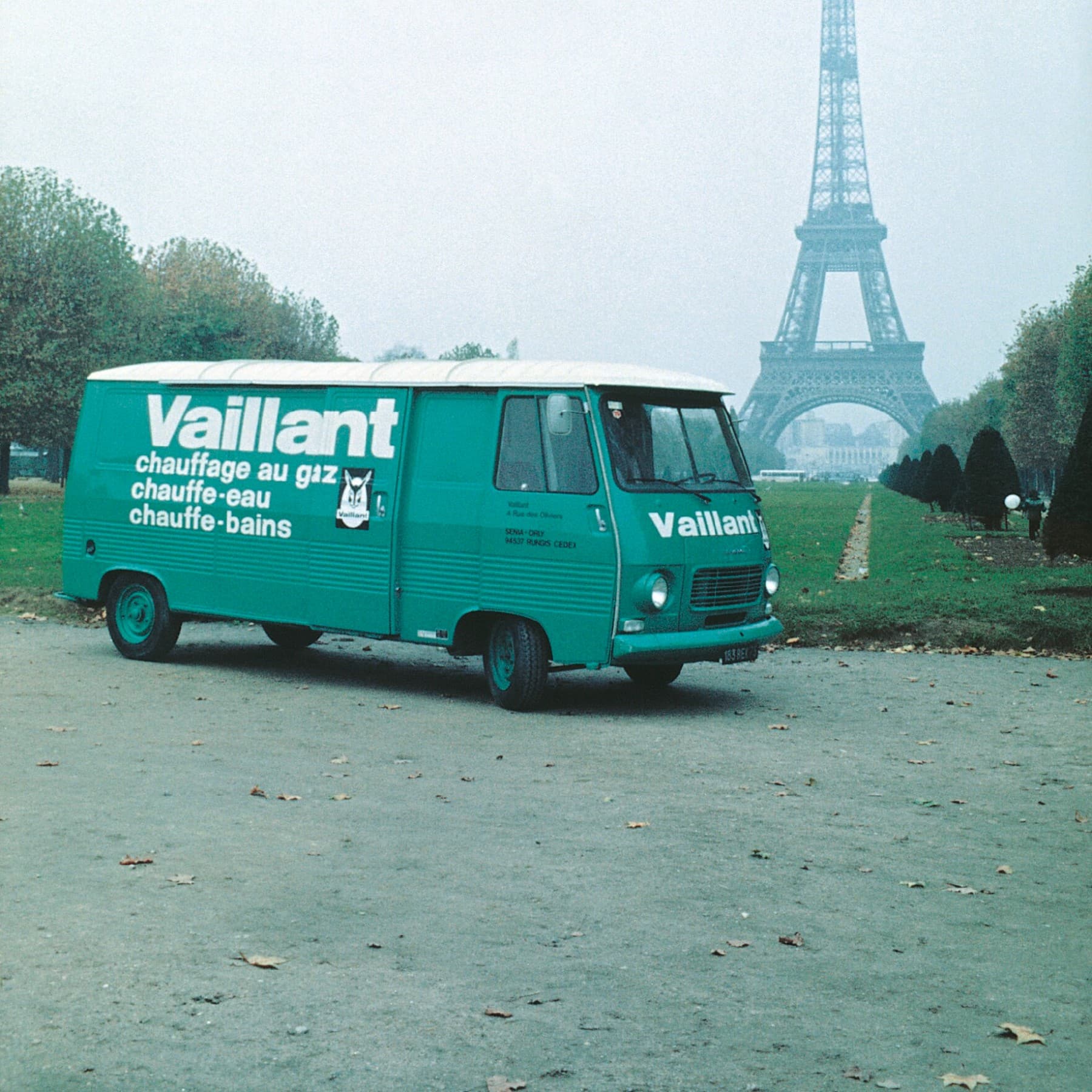 Ein alter Vaillant Bus steht in einem Park. Im Hintergrund ist der Eifelturm zu sehen.