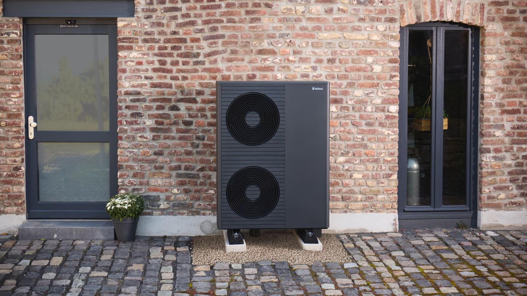 Schwarzgraue Vaillant Wärmepumpe vor einer Hauswand