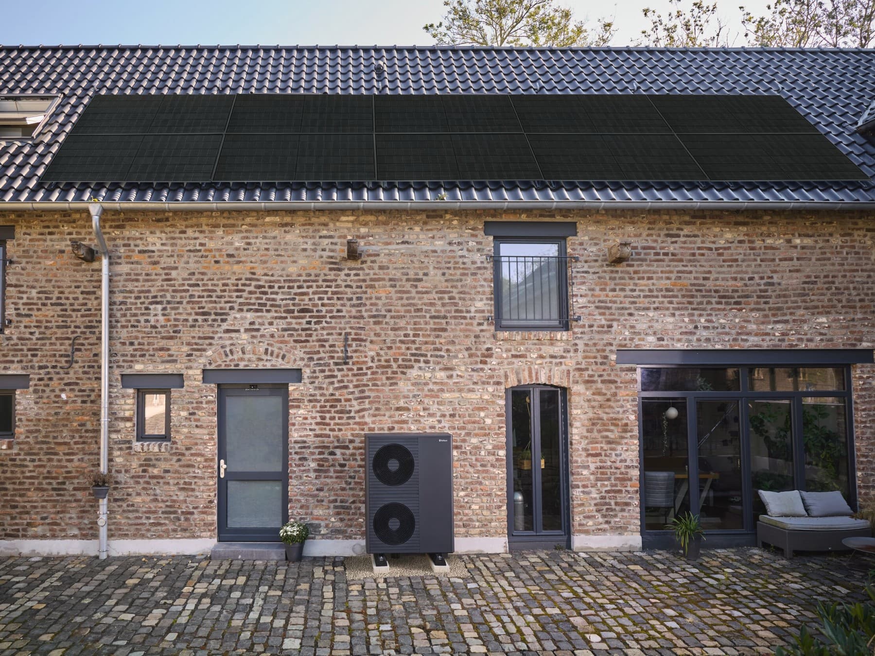 Eine neue Vaillant Wärmepumpe aroTHERM plus steht vor einem Backsteingebäude.