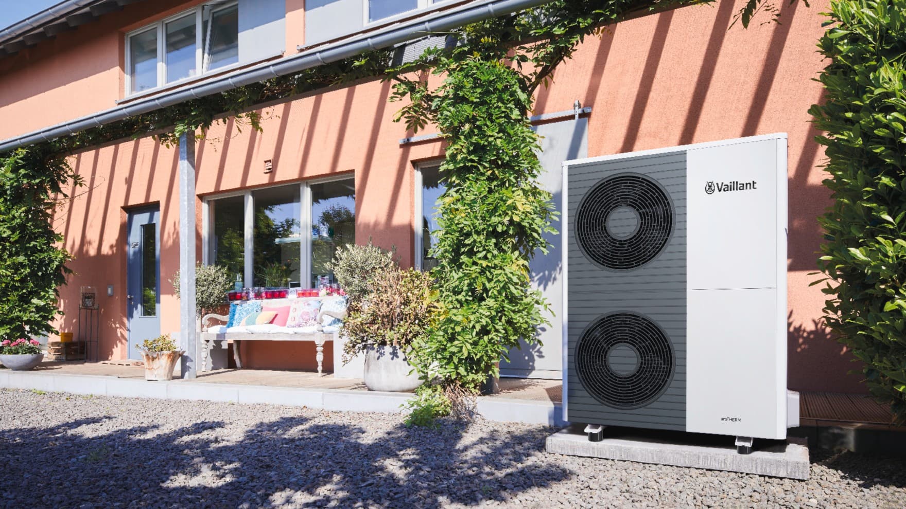 Eine aroTHERM Split Wärmepumpe von Vaillant steht vor einem Haus neben einer Terrasse.