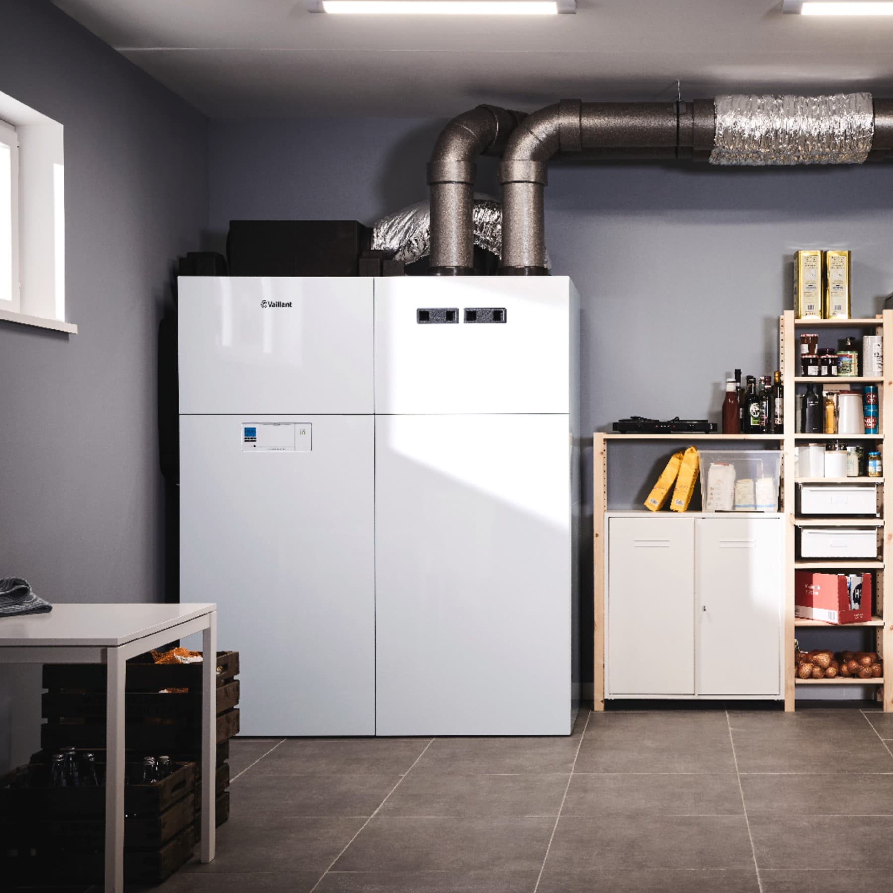 Die Vaillant recoCOMPACT exclusive steht in einem Haushaltsraum neben Regalen.