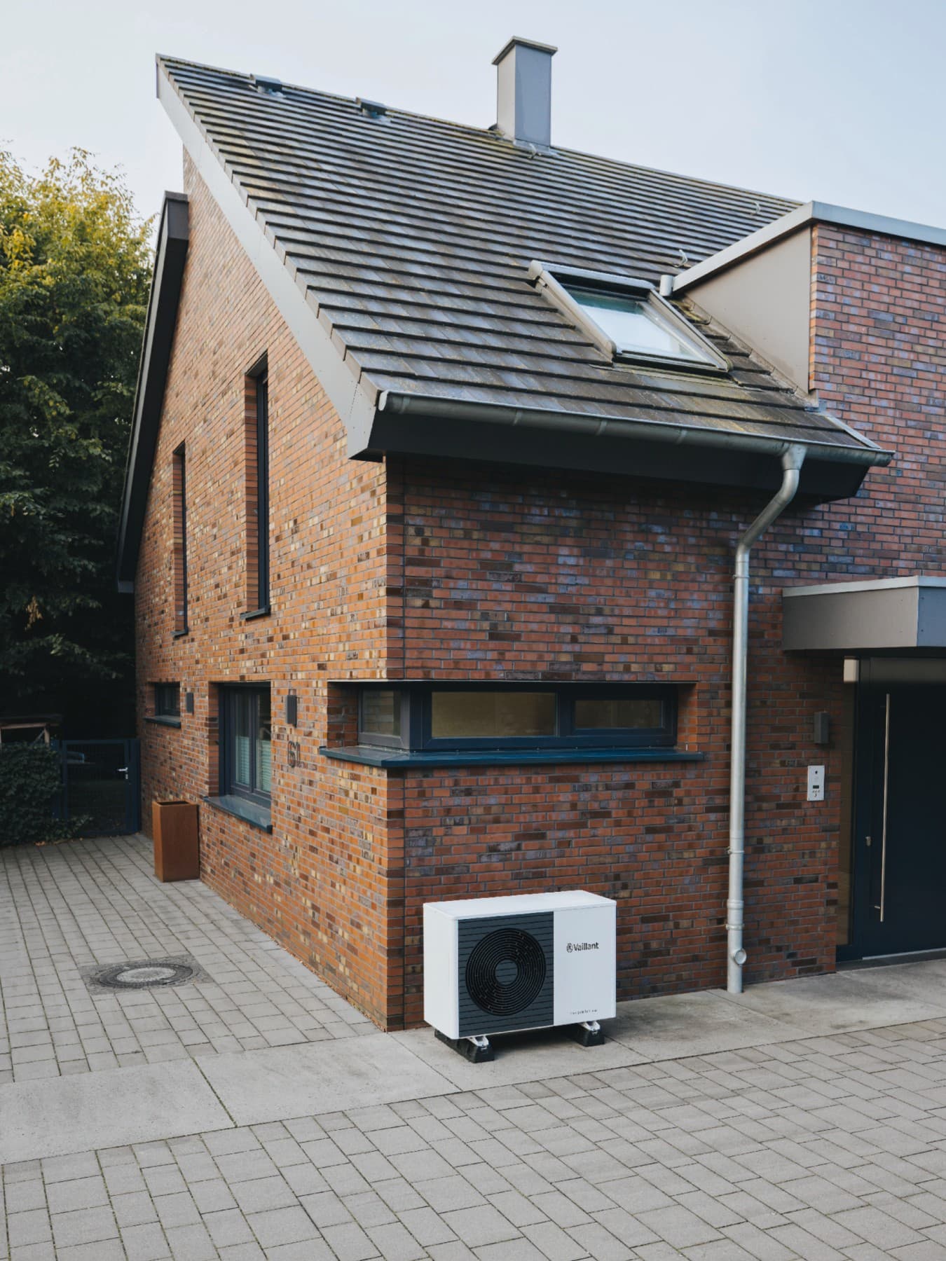 Sanierter Altbau, vor dem eine Vaillant Wärmepumpen Außeneinheit steht