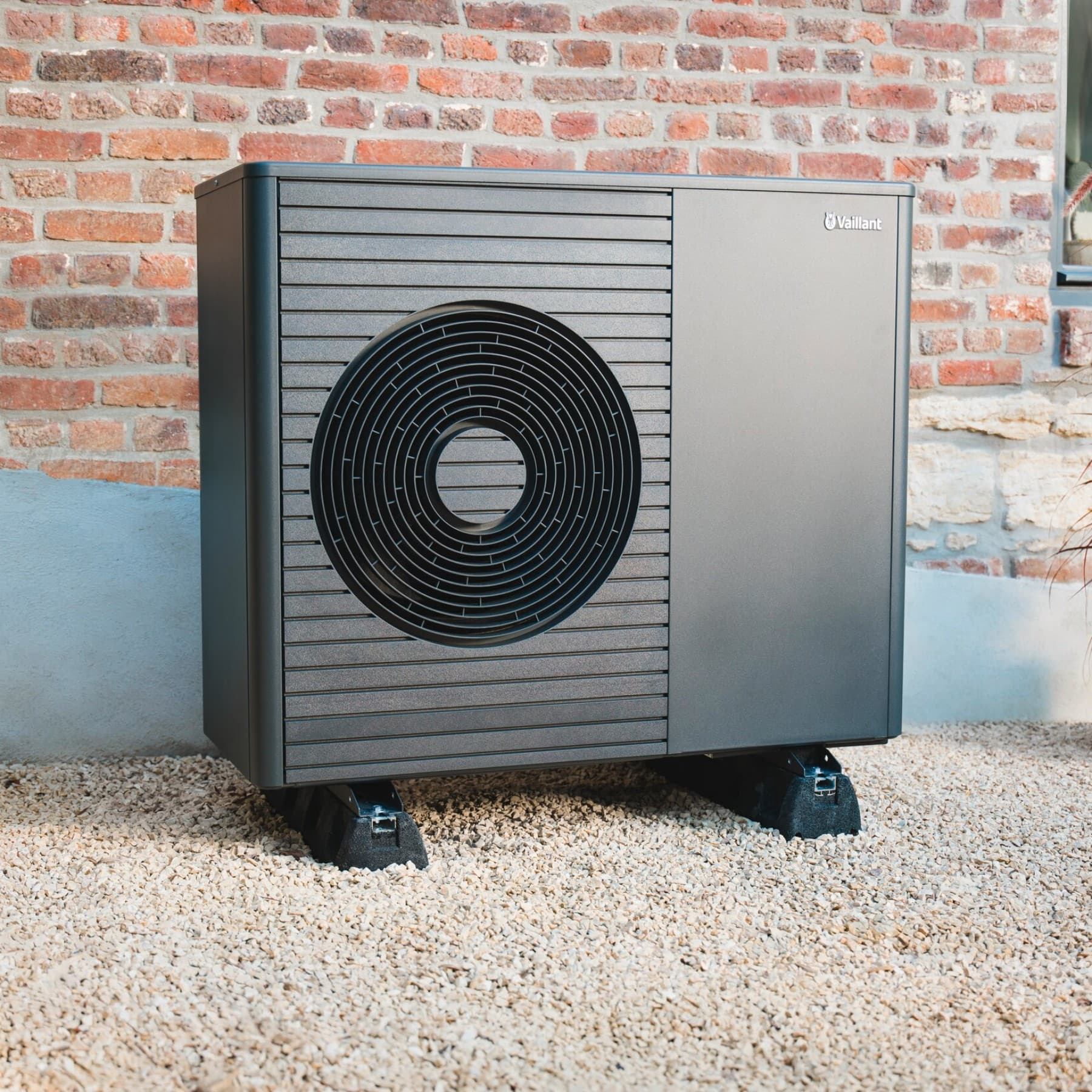 Wärmepumpen Außeneinheit aroTHERM plus, die vor einer Hauswand im Kies steht