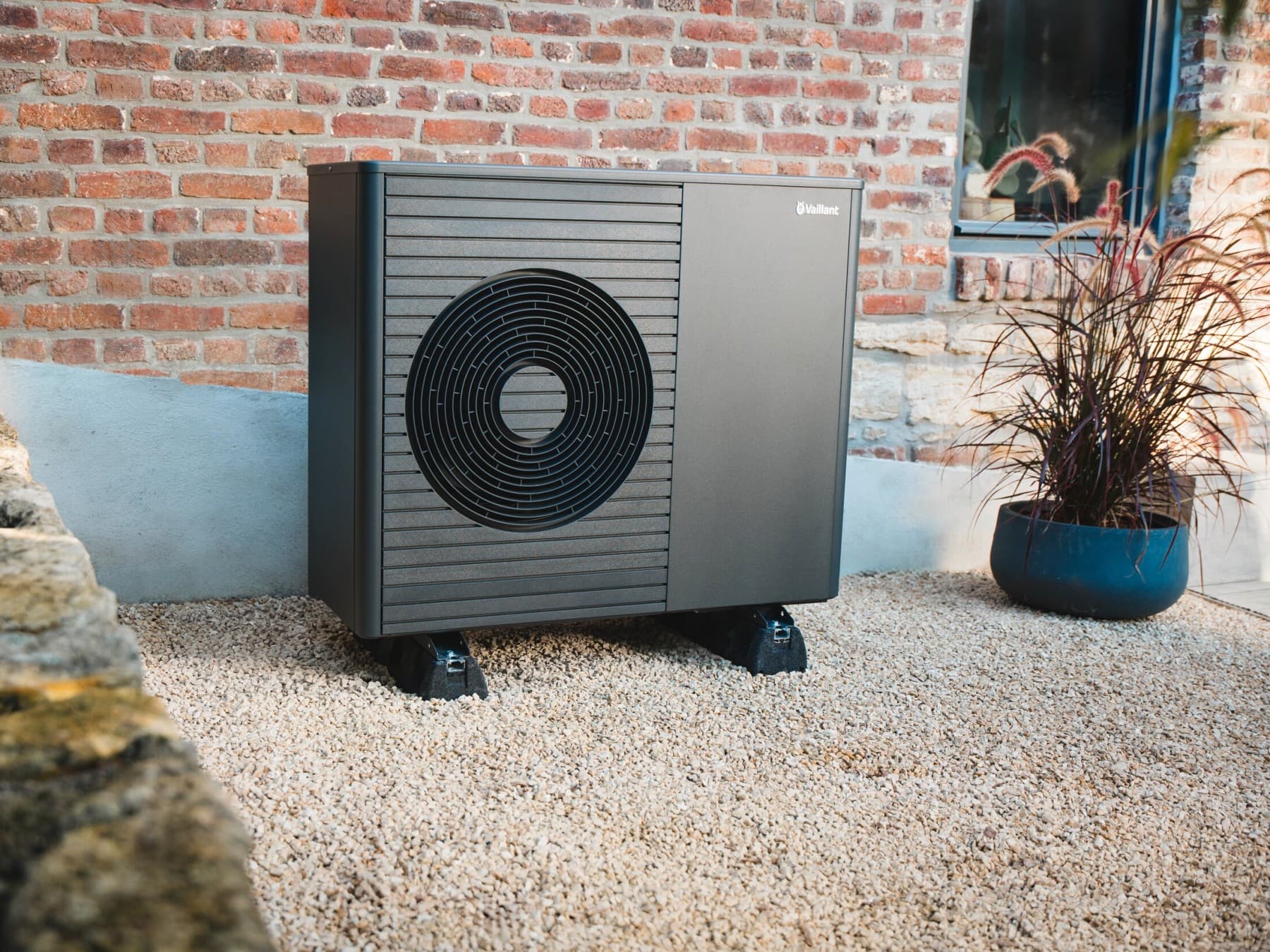 Außeneinheit der Vaillant Luft-Wasser-Wärmepumpe aroTHERM plus in Anthrazit im vor einem Backsteingebäude