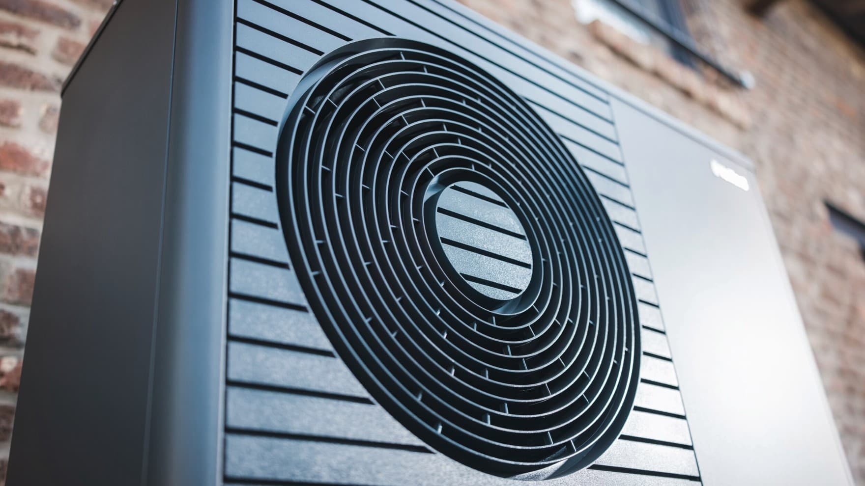 Schwarzgraue Vaillant aroTHERM plus Wärmepumpe vor einer Hauswand