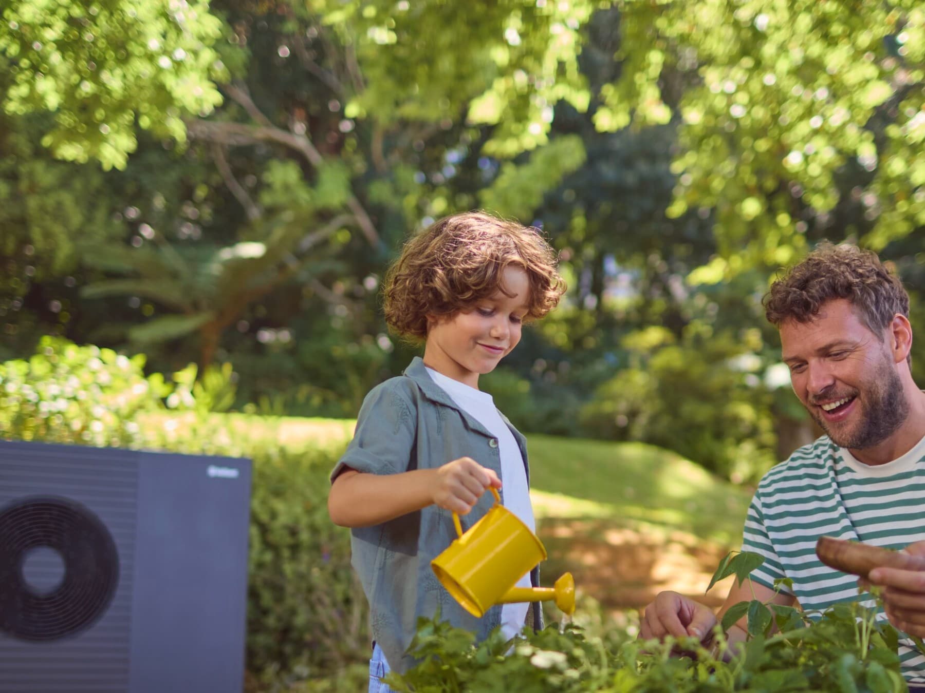 Vater und Kind im Garten vor einer Vaillant Wärmepumpe