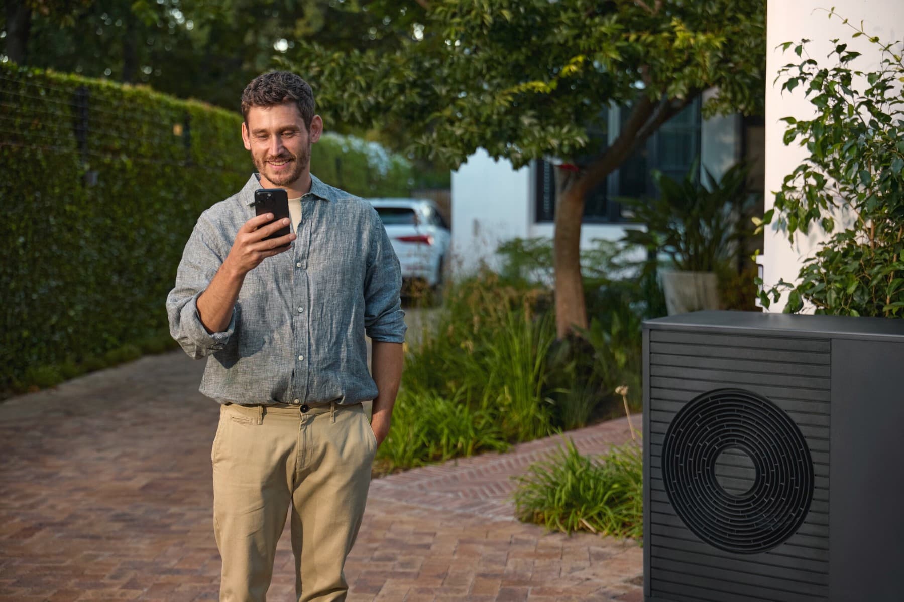 Mann mit Smartphone vor Wärmepumpe