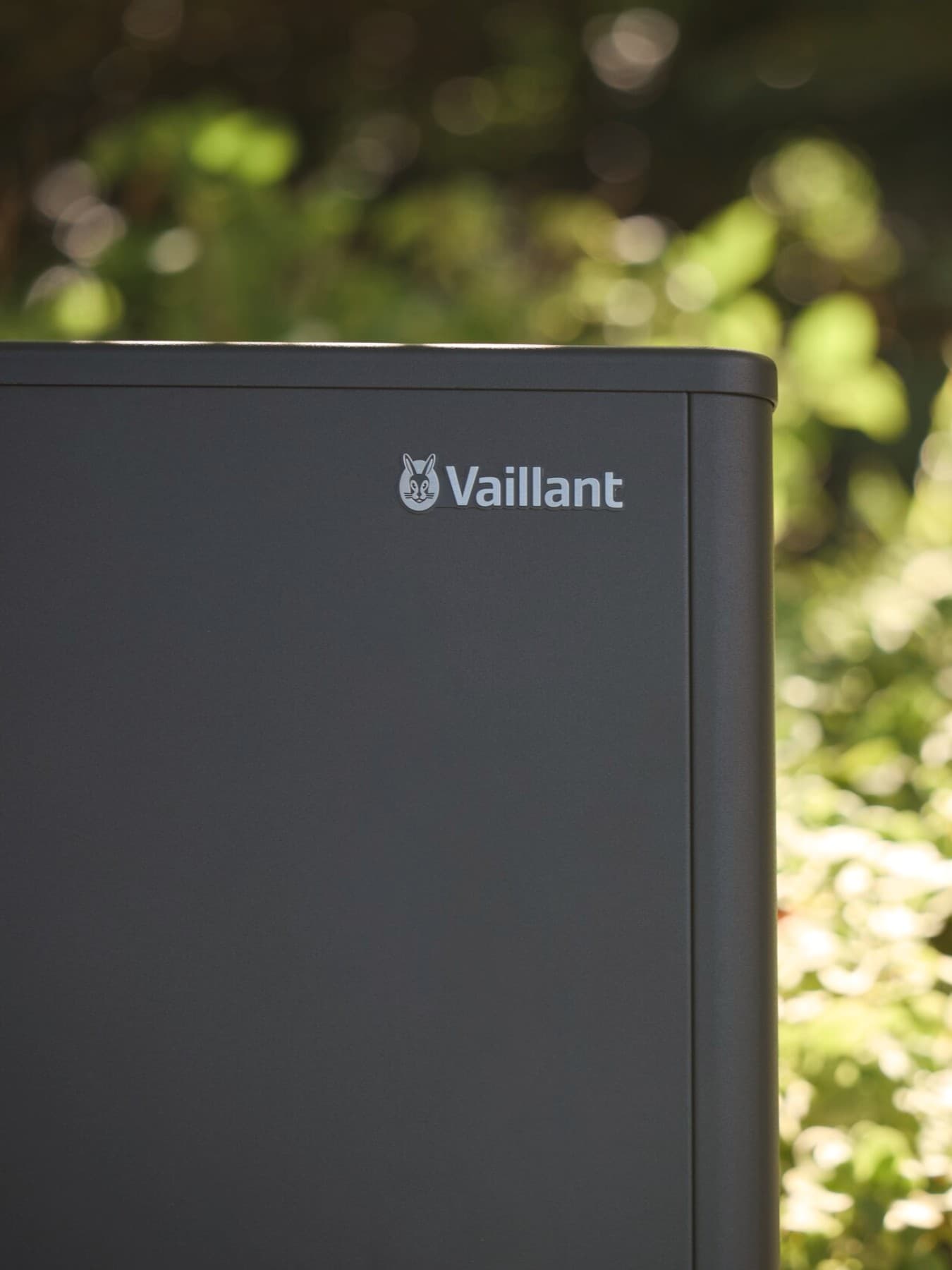 Ein Ausschnitt der neuen Vaillant aroTHERM plus Wärmepumpe mit grünen Blättern im Hintergrund.