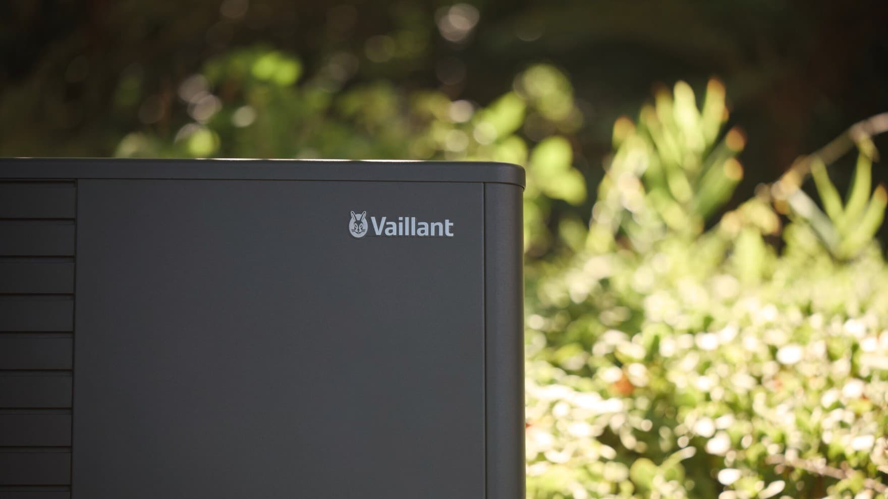 Nahaufnahme Wärmepumpe aroTHERM plus im Garten mit Bäumen im Hintergrund