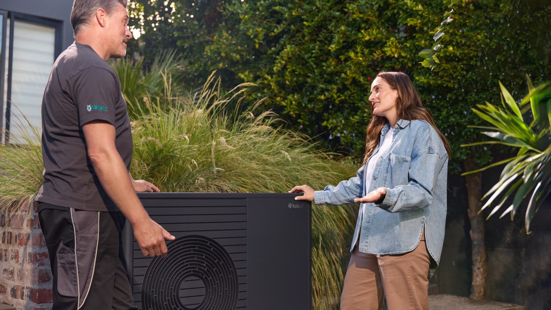 Vaillant Fachpartner und Endkundin stehen gemeinsam an der Wärmepumpe im Garten