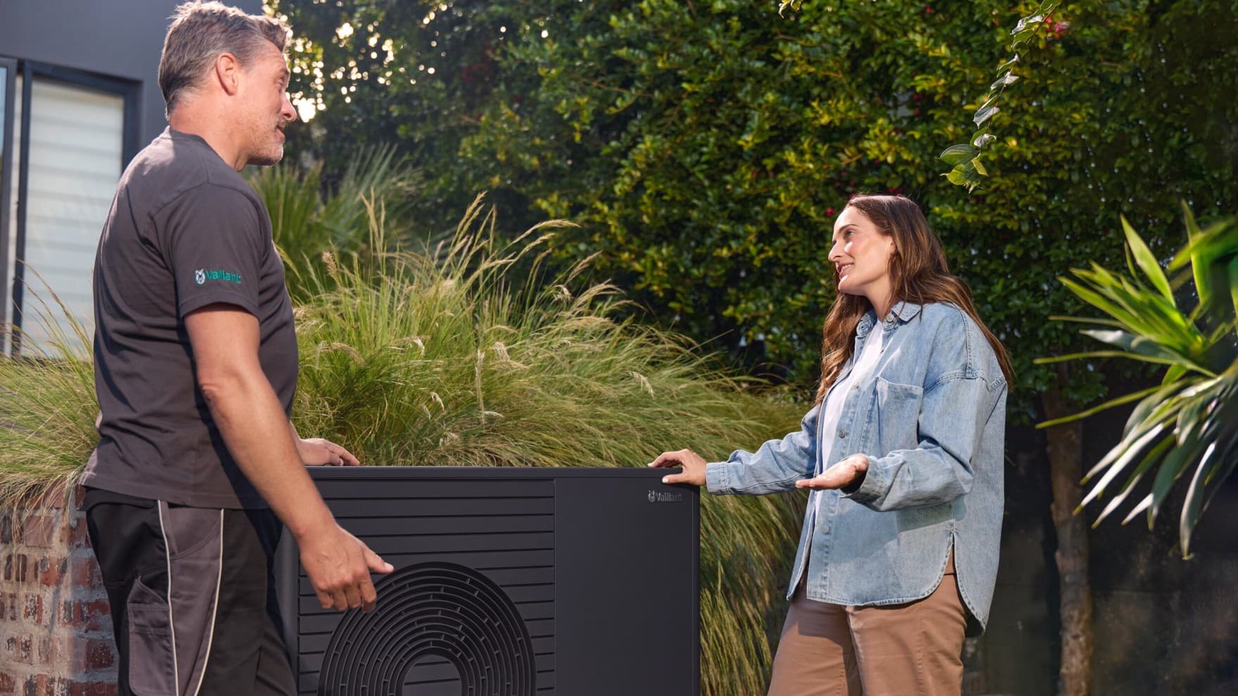 Vaillant Techniker mit Frau vor Wärmepumpe.