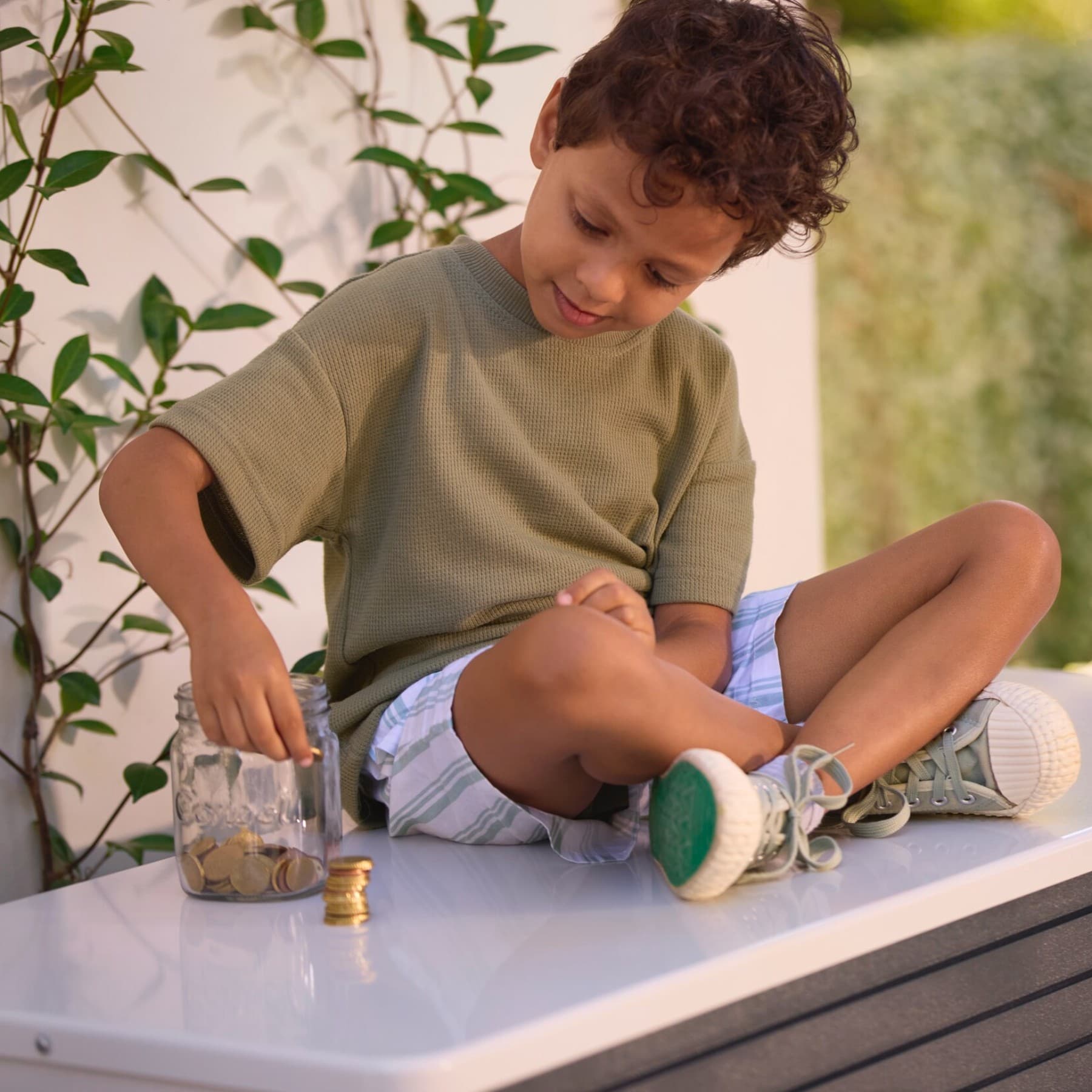 Kind, das auf einer Vaillant Wärmepumpe sitzt und Münzen zählt