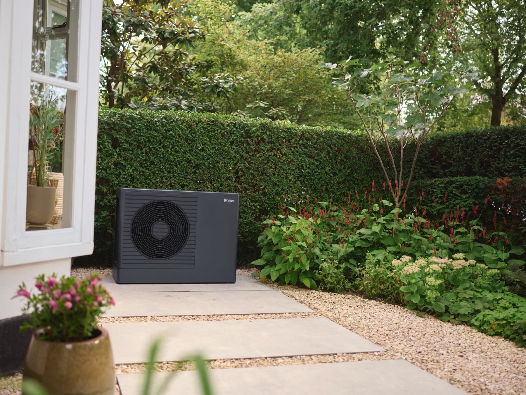 Wärmepumpe aroTHERM plus von Vaillant vor einer Hauswand auf dem Grundstück aufgestellt.