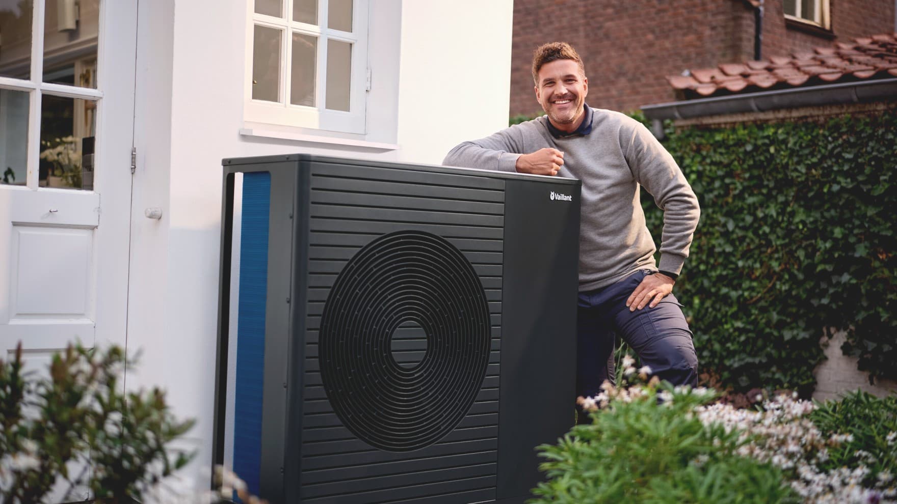 Vaillant Wärmepumpe aroTHERM pro vor einem weißen Haus mit einem freundlichen Mann