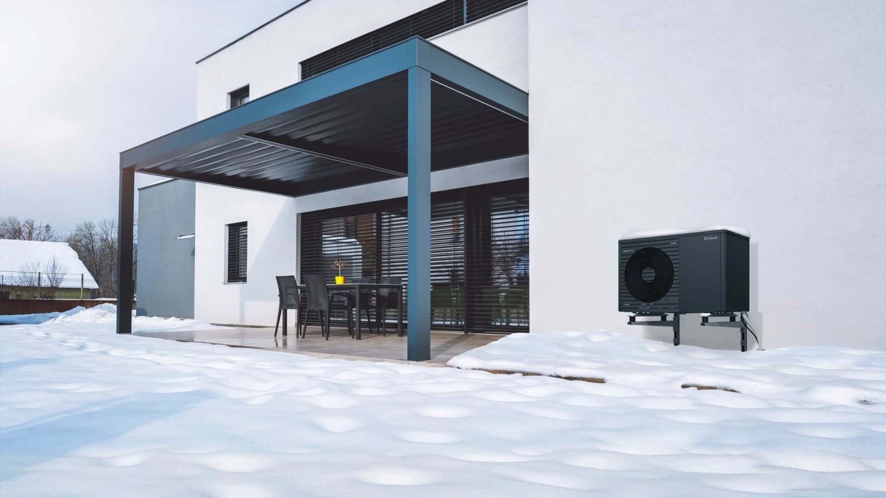 Luft-Wasser-Wärmepumpe aroTHERM plus von Vaillant vor einem Einfamilienhaus im Schnee