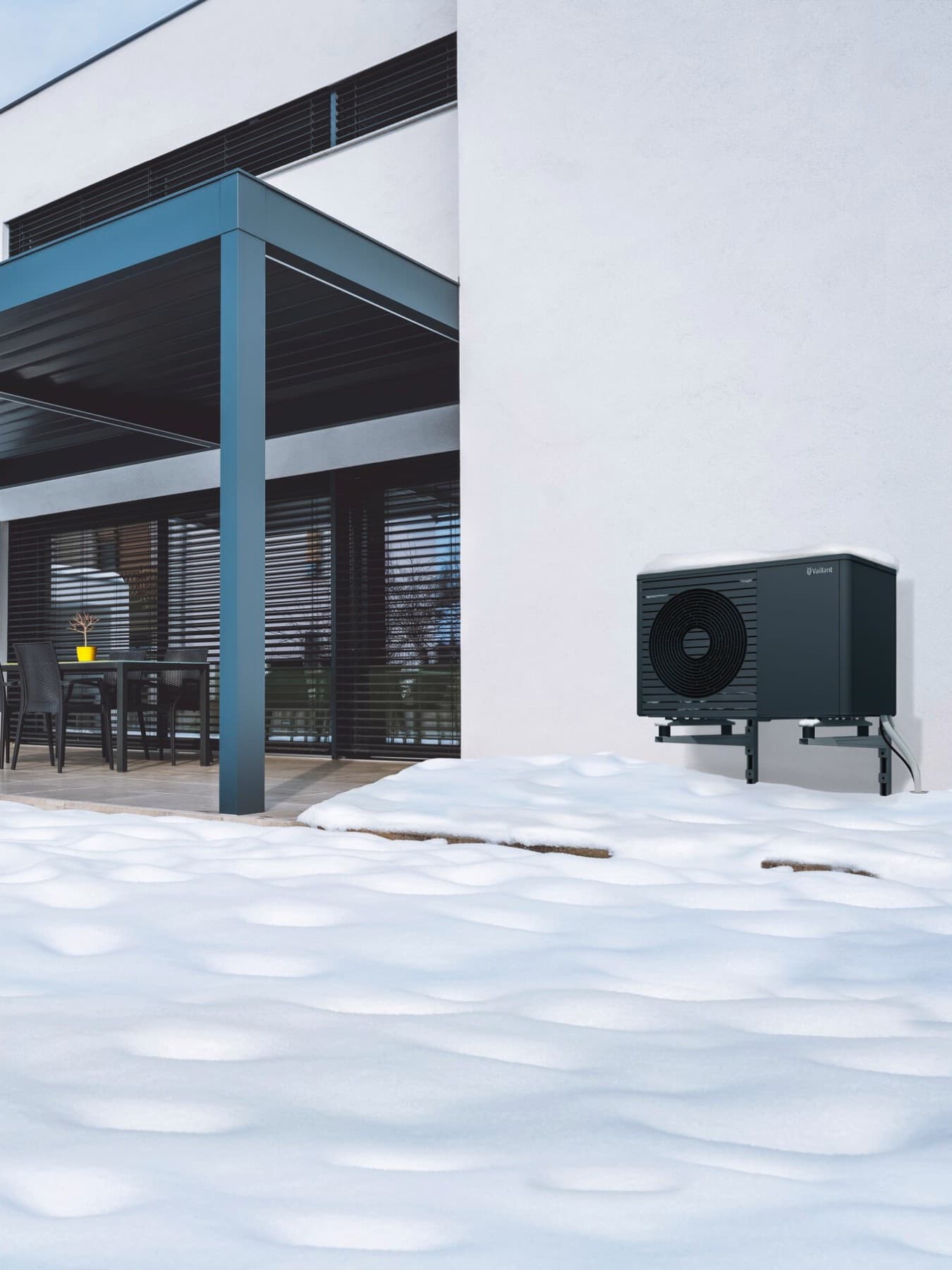 Luft-Wasser-Wärmepumpe aroTHERM plus von Vaillant vor einem Einfamilienhaus im Schnee