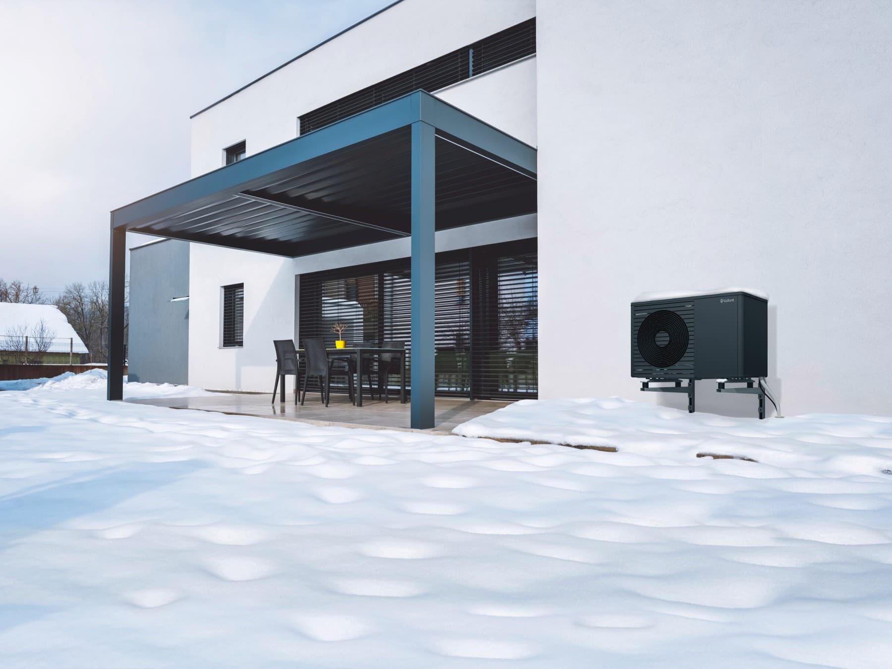 Mehrfamilienhaus mit einer schwarzgrauen Vaillant Wärmepumpe auf einer Halterung an der Hauswand