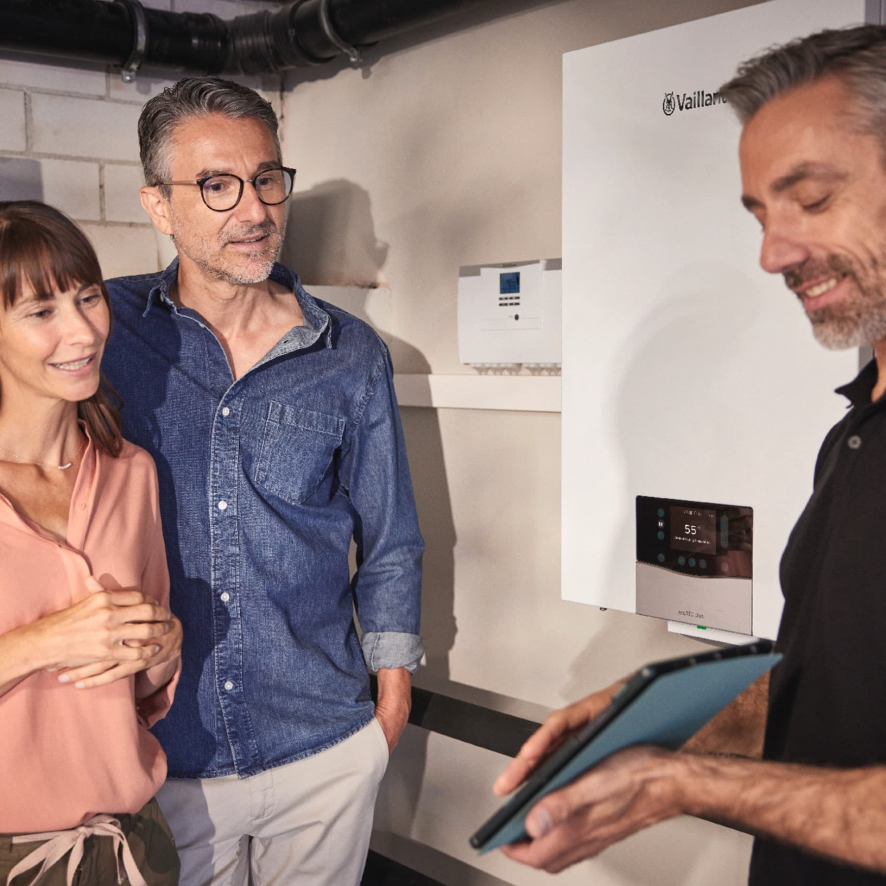 Kunden mit einem Fachhandwerker vor einer Hybridheizung