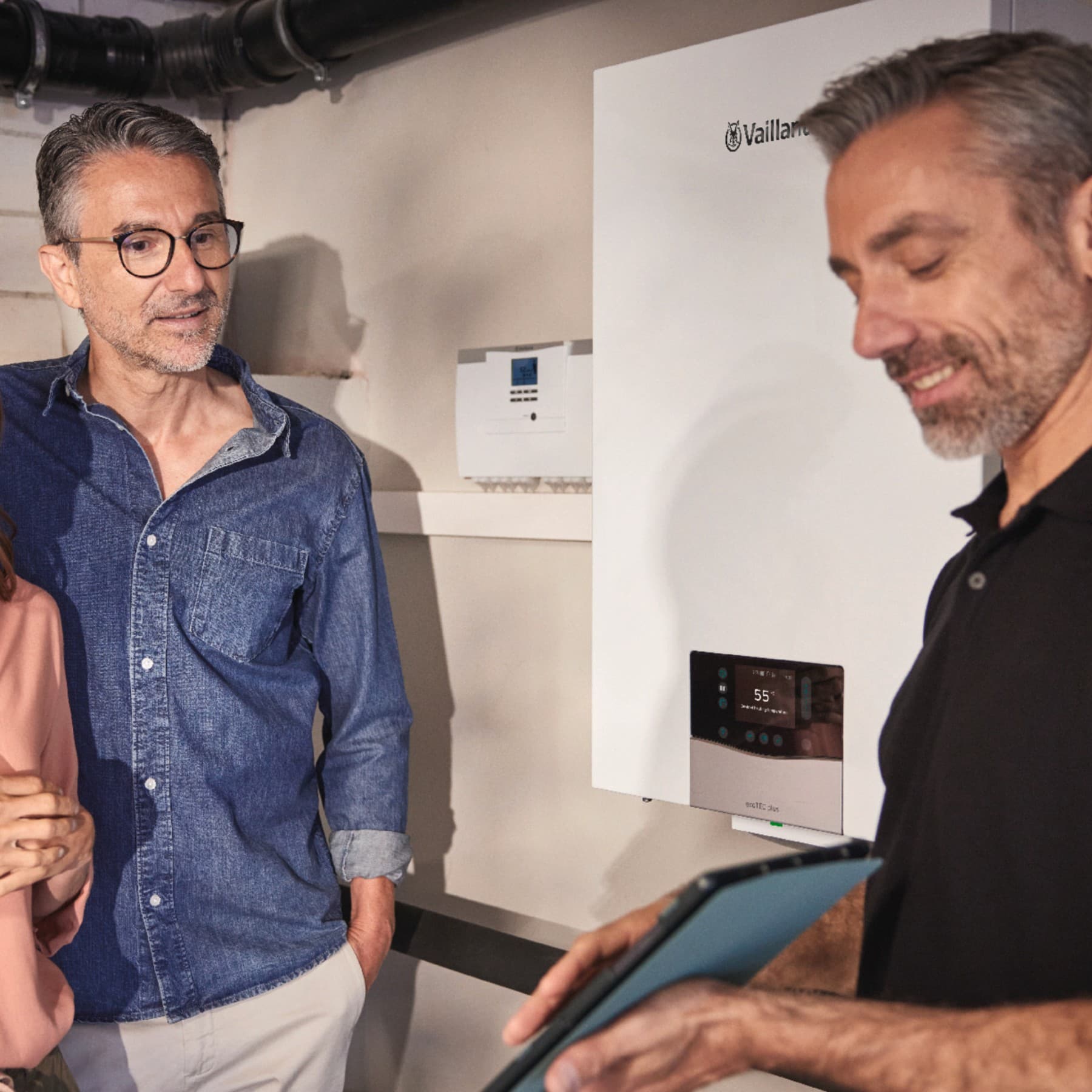 Ehepaar und Fachhandwerker im Heizungskeller