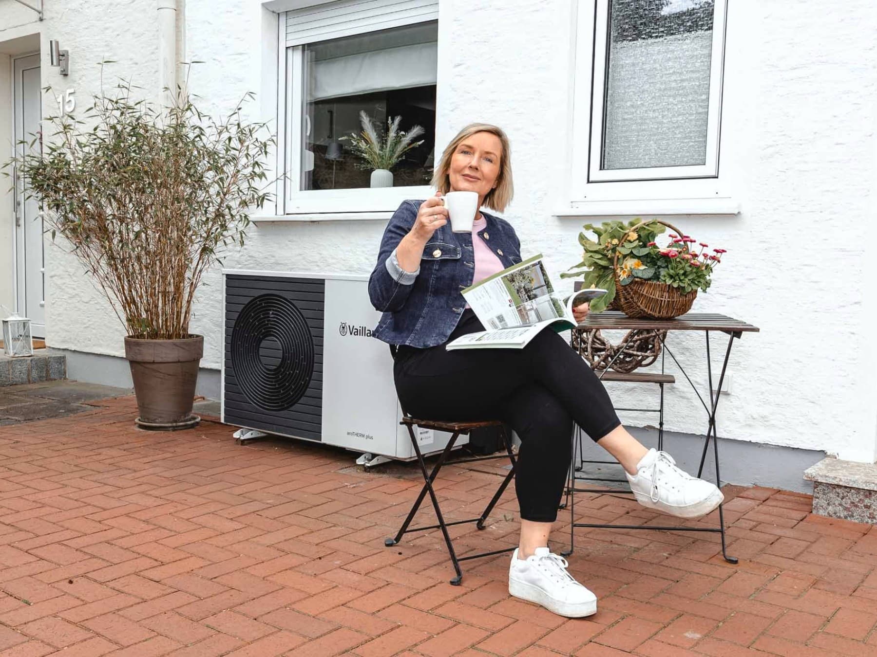 Frau auf einem Gartenstuhl sitzend neben der Wärmepumpe