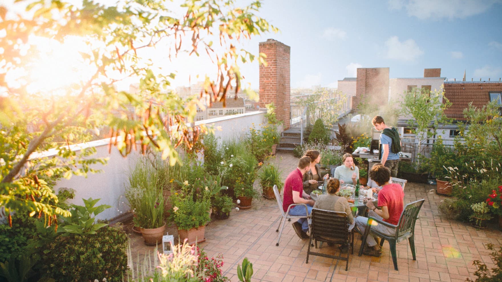 Junge Wohnungsbesitzer bei der Eigentumssitzung auf der grünen Dachterrasse ihres Mehrfamilienhauses