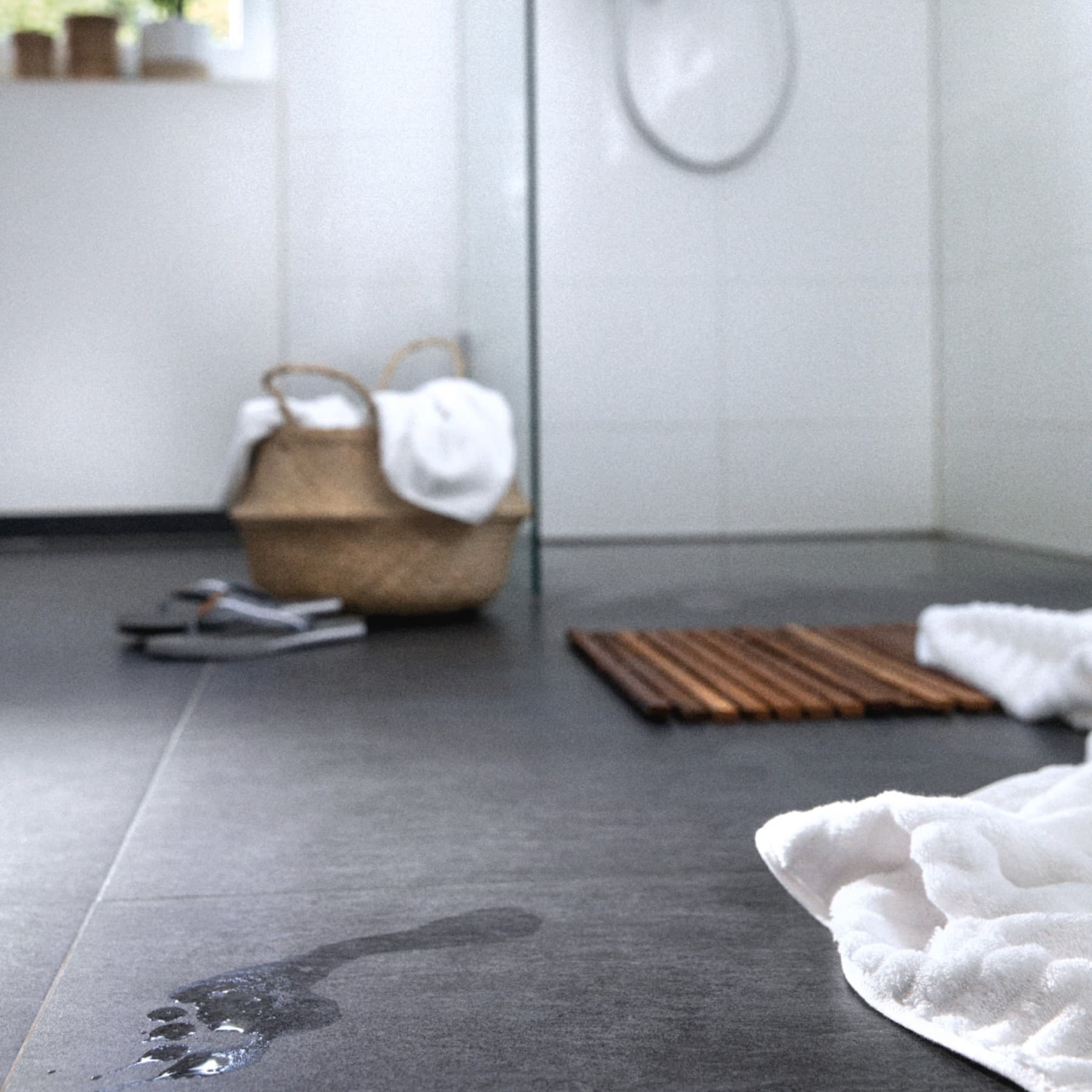 Leere Dusche mit nassem Fußabdruck im Vordergrund.