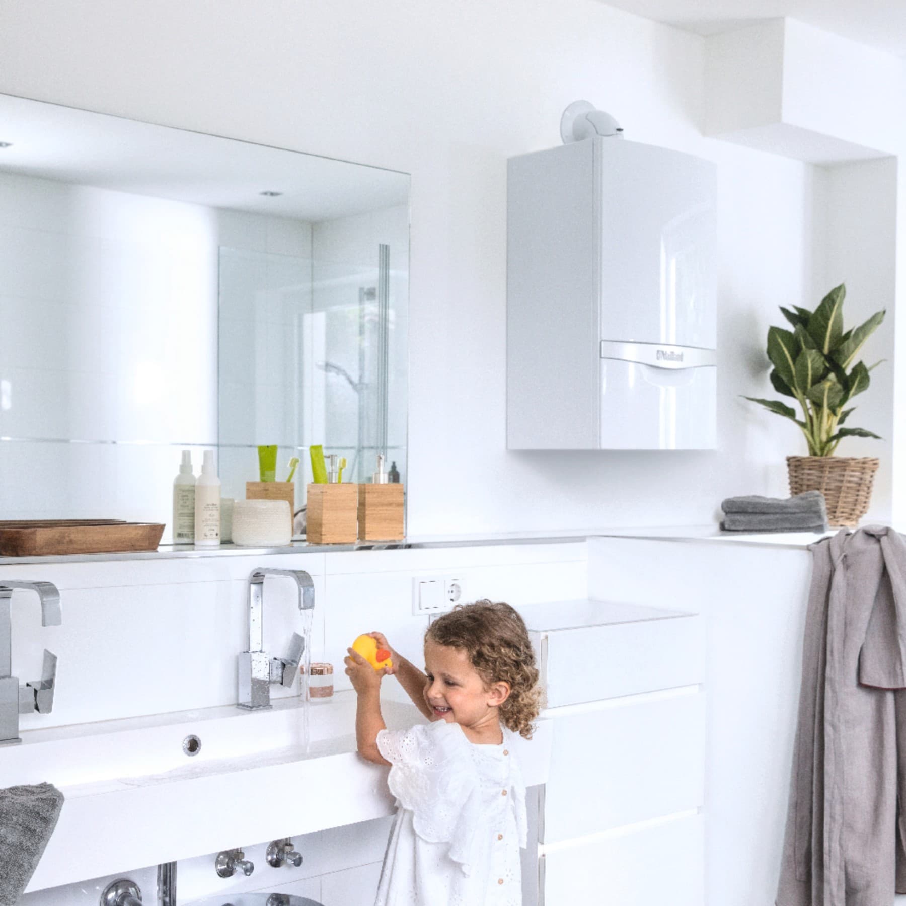Kind am Waschbecken. Im Hintergrund hängt ein Vaillant Gerät an der Wand.