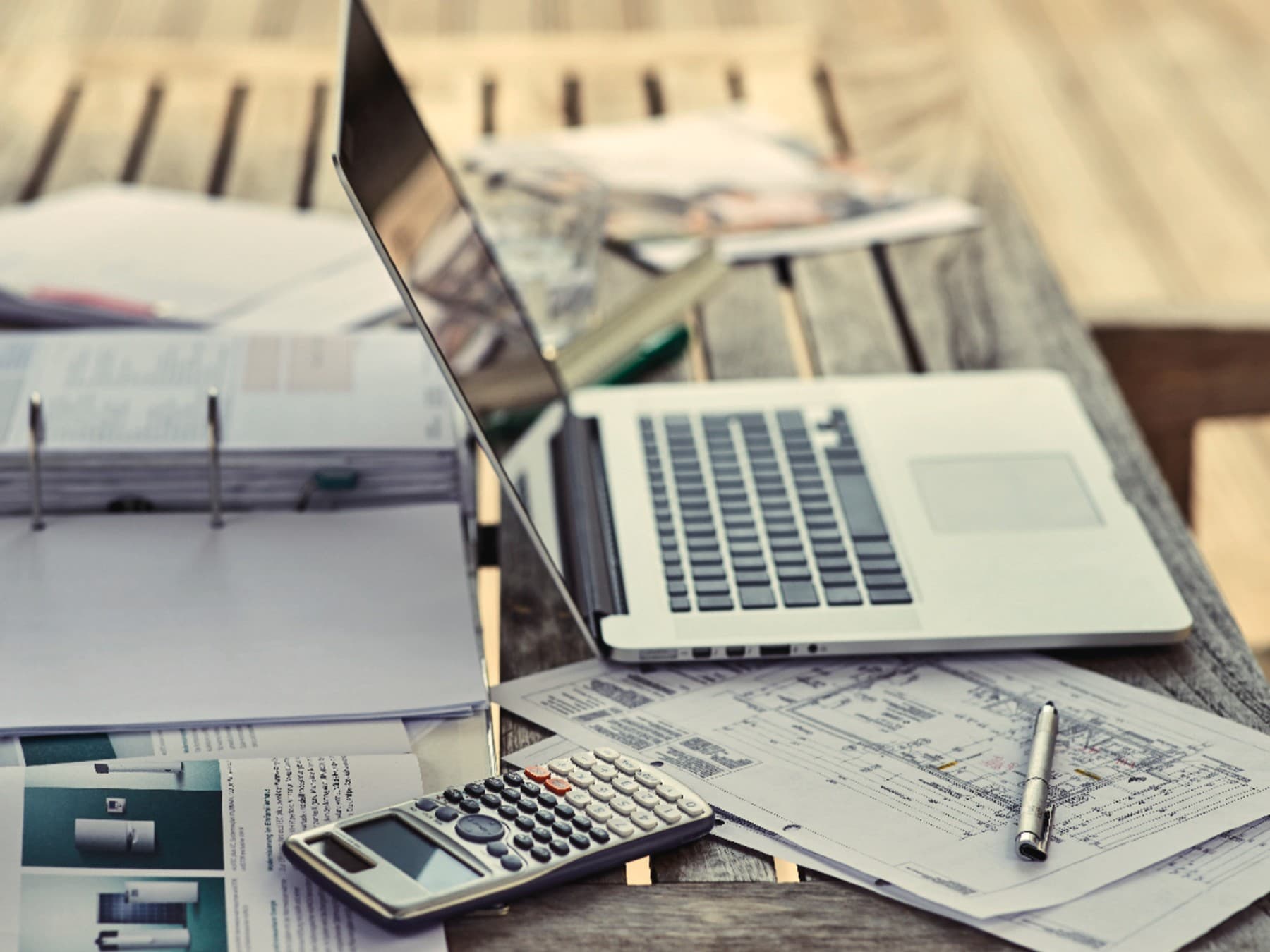 Laptop, der auf einem Tisch neben Unterlagen steht