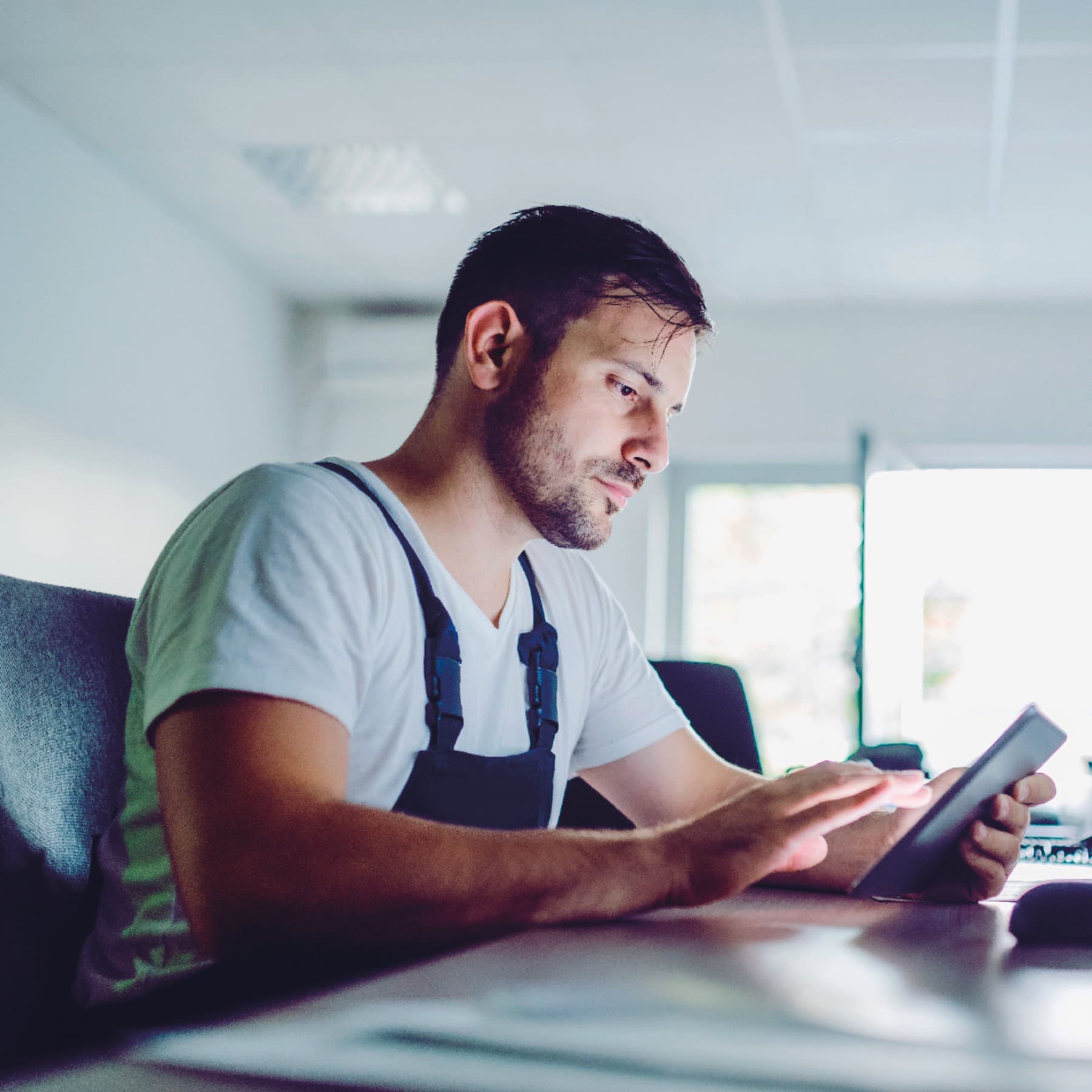 Fachhandwerker sitz in seinem Schreibtisch mit Tablet und Laptop