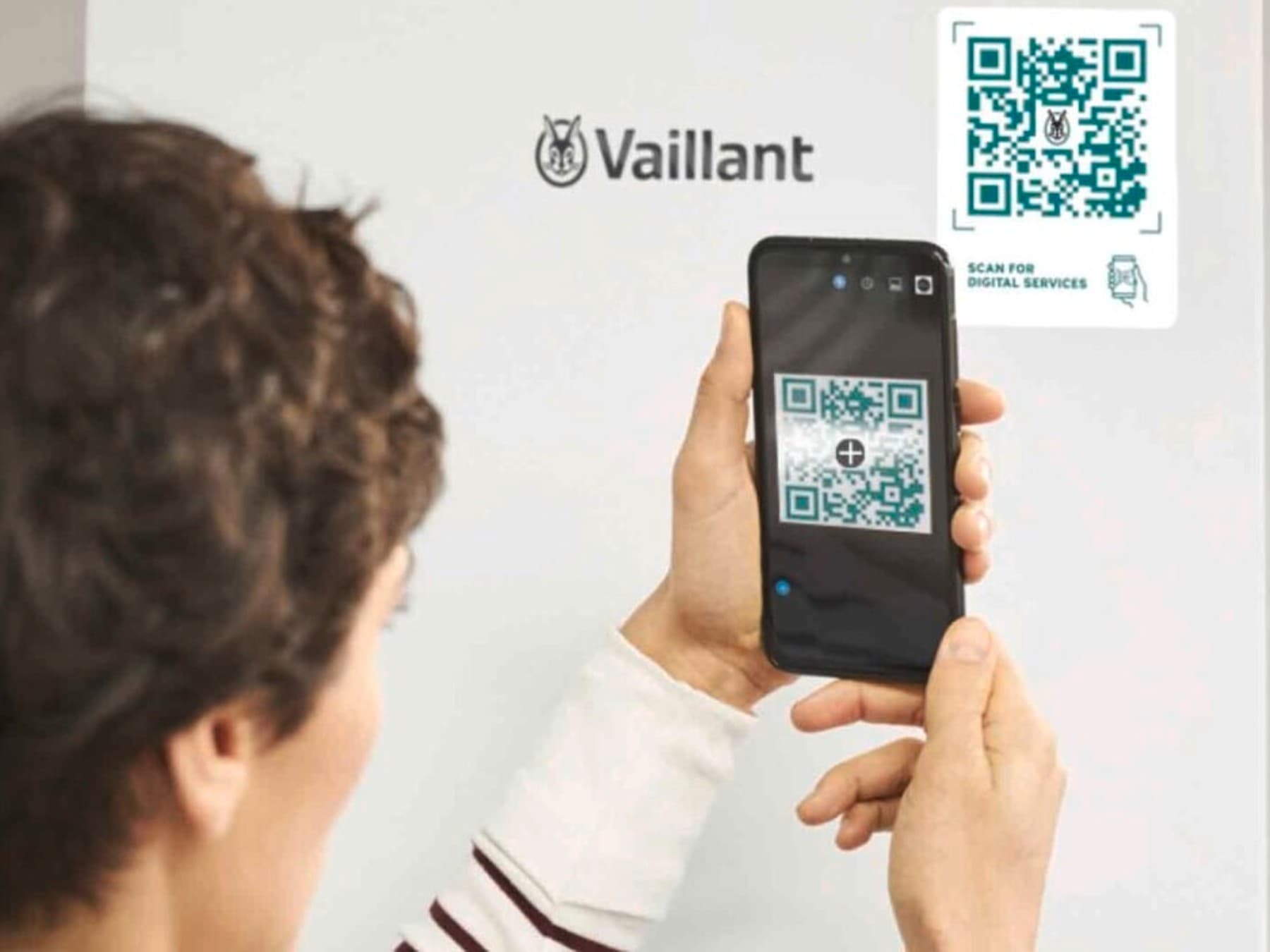 Frau, die vor einem Vaillant Heizgerät steht und einen QR Code scannt