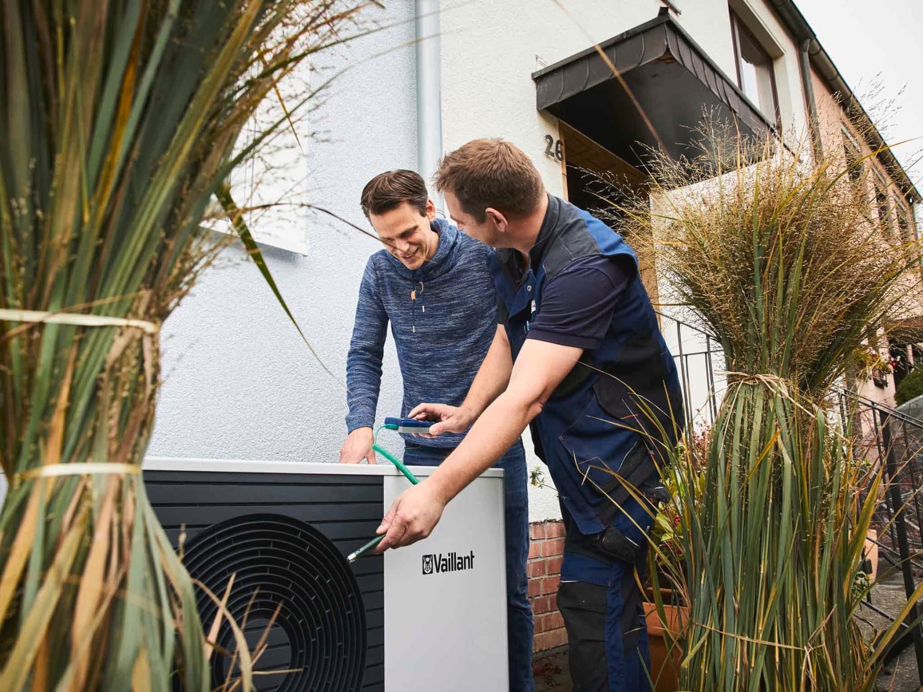 Zwei Männer stehen an der Außeneinheit einer Wärmepumpe