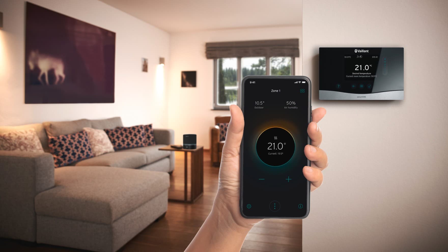 Nahaufnahme einer Hand, die ein Smartphone in der Hand halt mit geöffneter myVAILLANT App. Im Hintergrund hängt der Regler an der Wand.