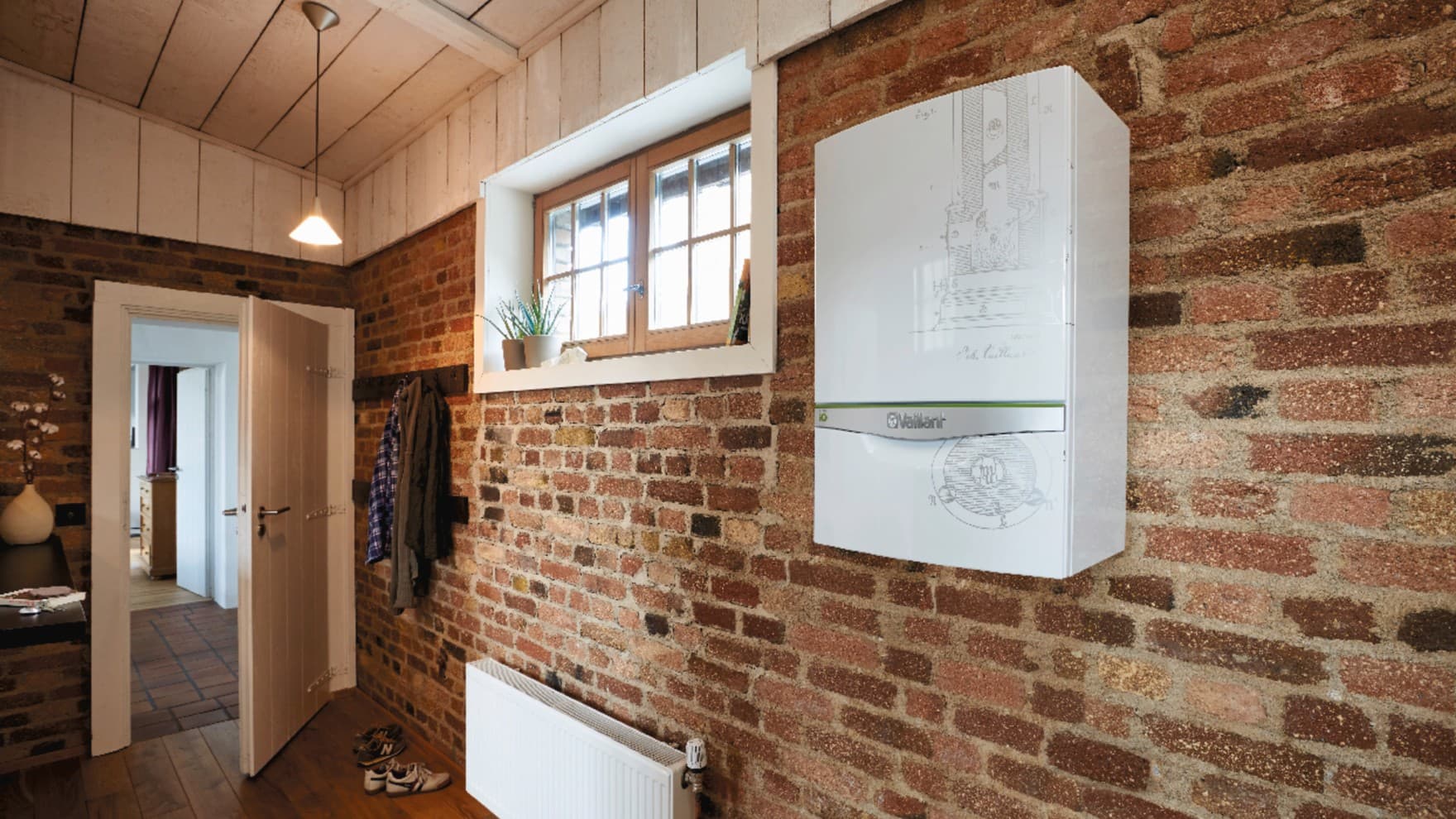 Ein Heizkörper und ein Vaillant Heizgerät hängen an einer Backsteinwand in einem Kellerraum.