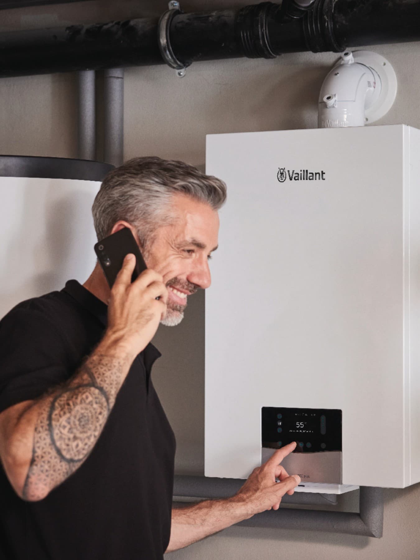 Eine Mann telefoniert und stellt etwas am Heizungsregler ein.